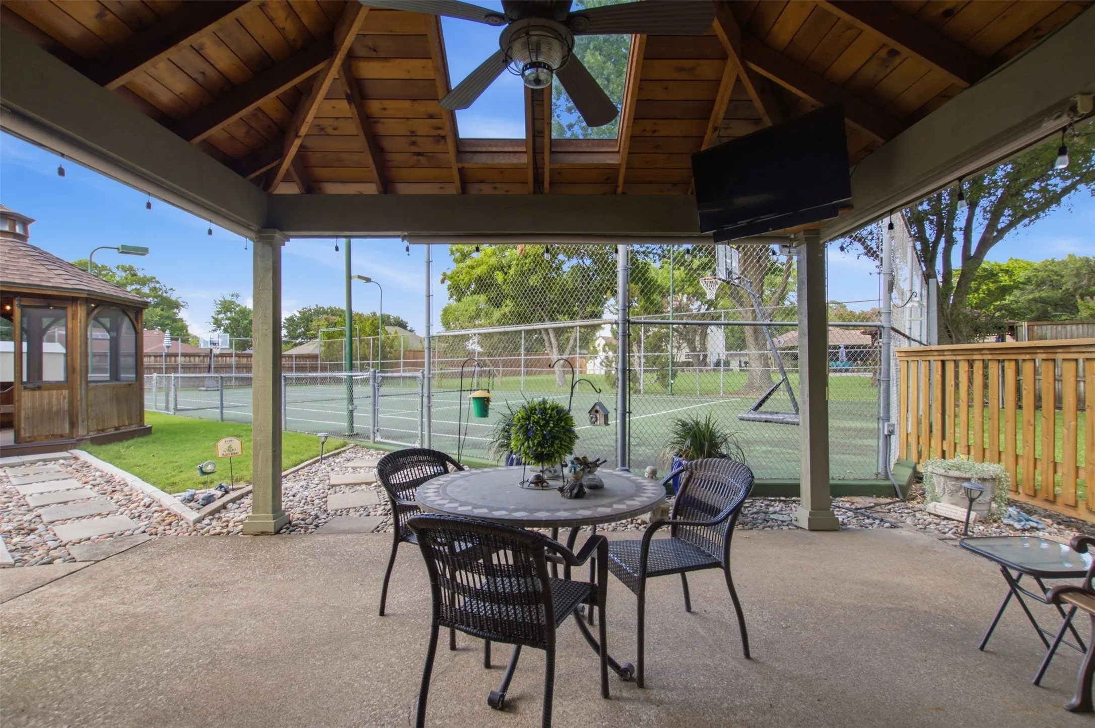 Covered patio with a wood-plank ceiling, ceiling fan and skylight