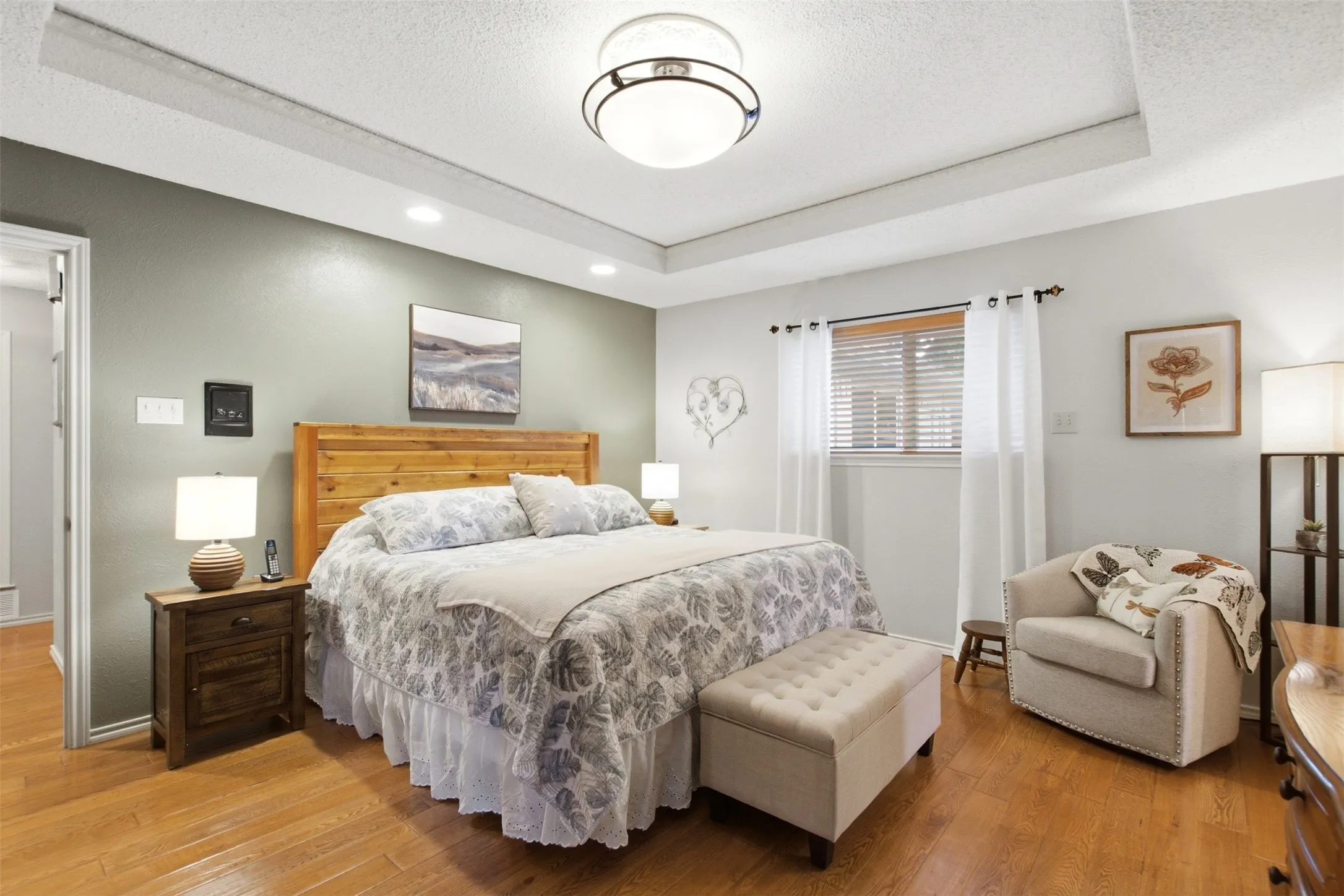 Hardwood-finish flooring throughout, featuring a tray ceiling with recessed lighting and a central flush-mount fixture