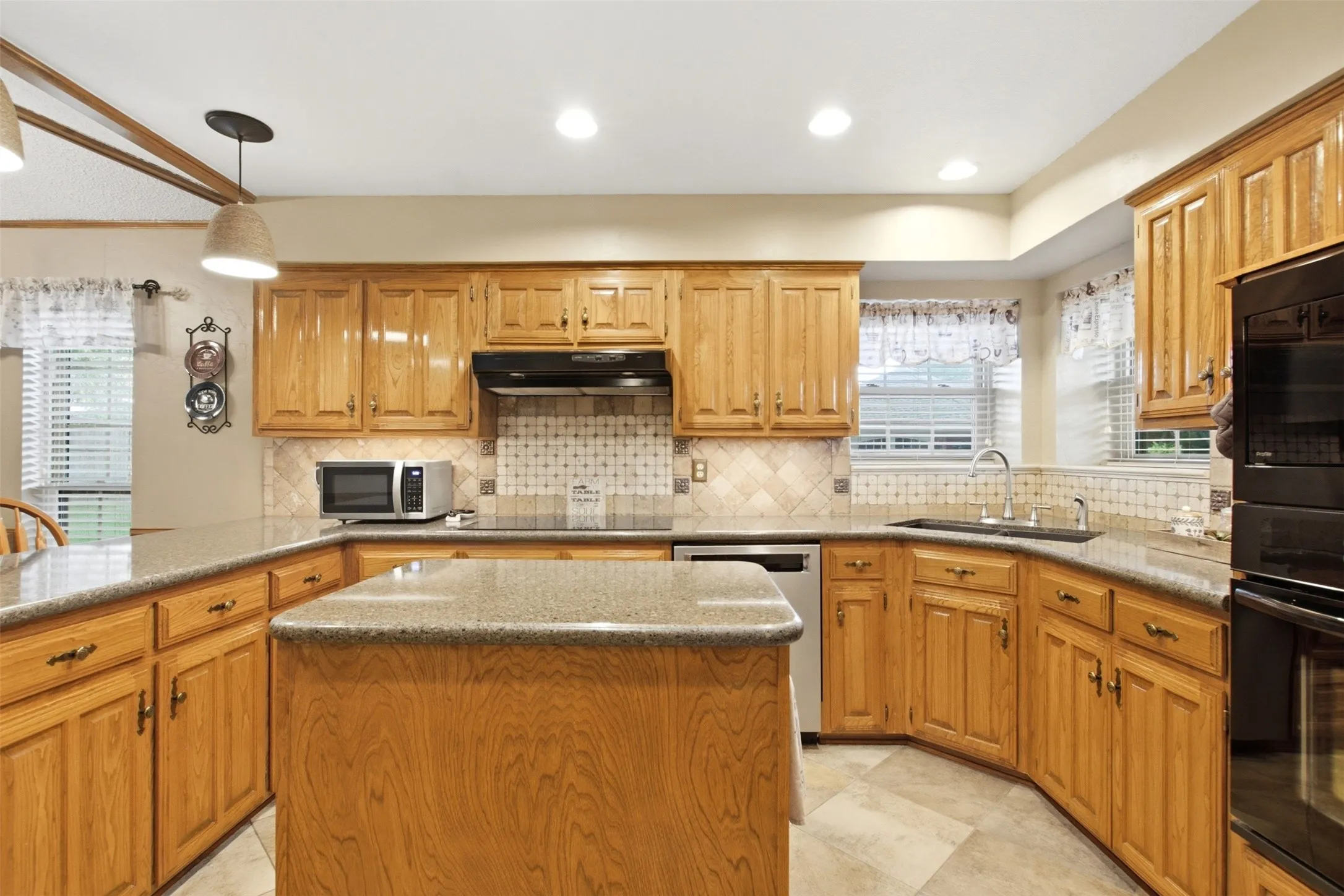Kitchen featuring wood-finish cabinetry, stone-look countertops, and a central island