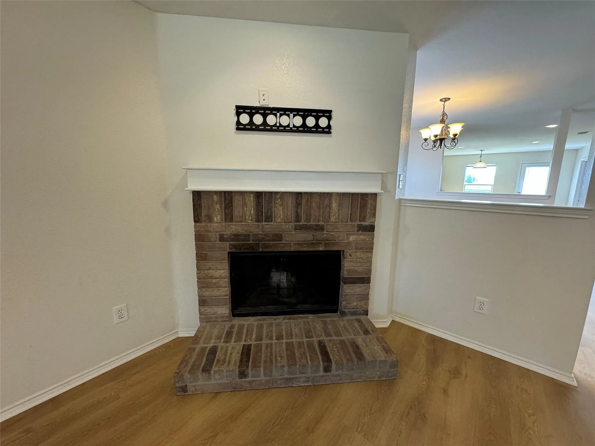 Corner fireplace with a brick surround and hearth, featuring a white mantel