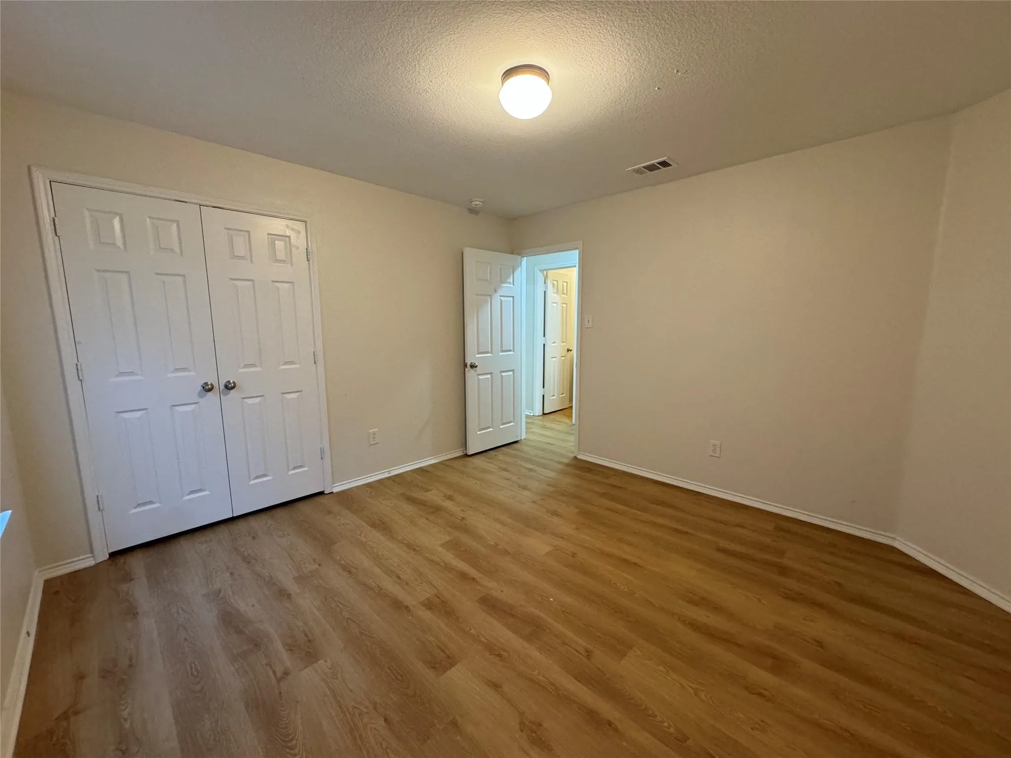 Room featuring wood-finish flooring, neutral wall tones, and a flush-mount ceiling light