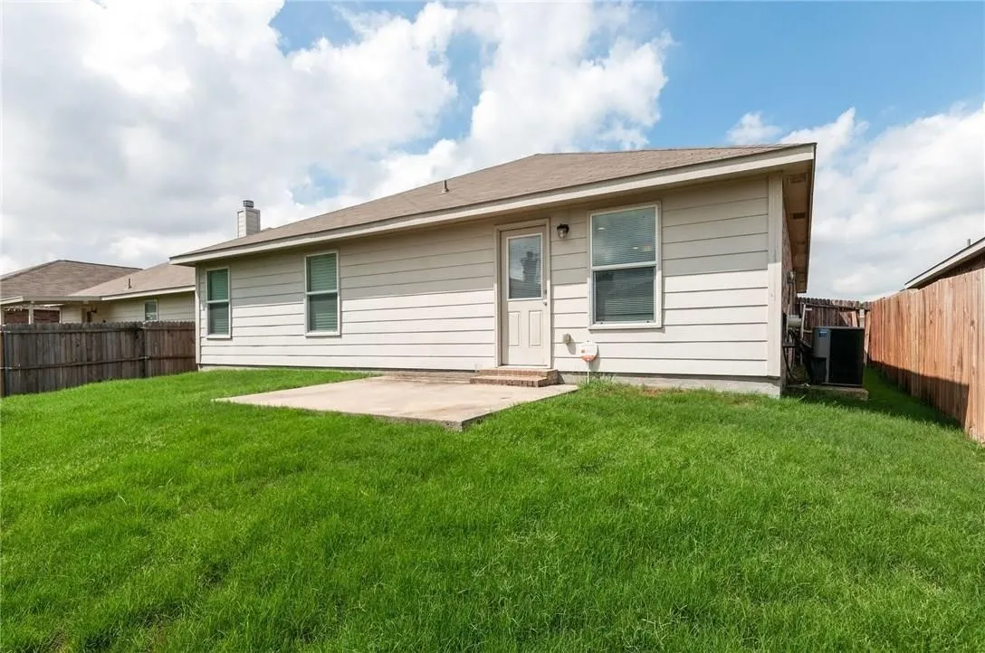 Expansive backyard featuring a lush lawn, concrete patio, and complete privacy fencing