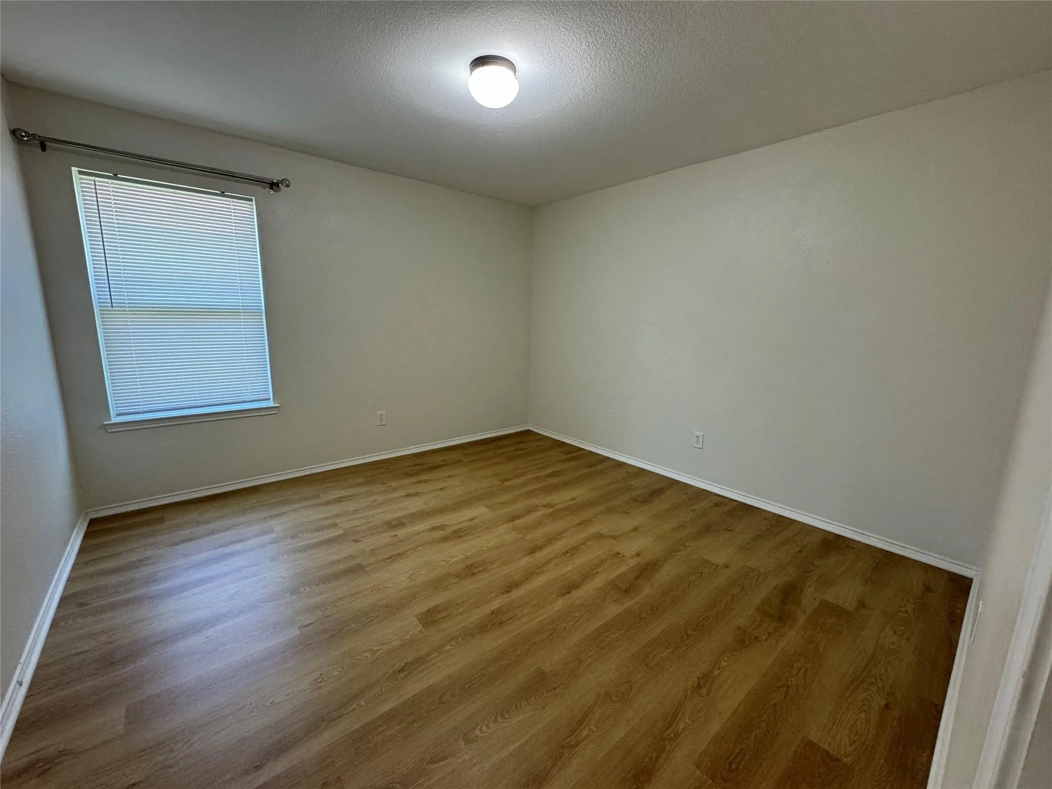 Room featuring wood-finish flooring, white baseboards, and neutral wall tones