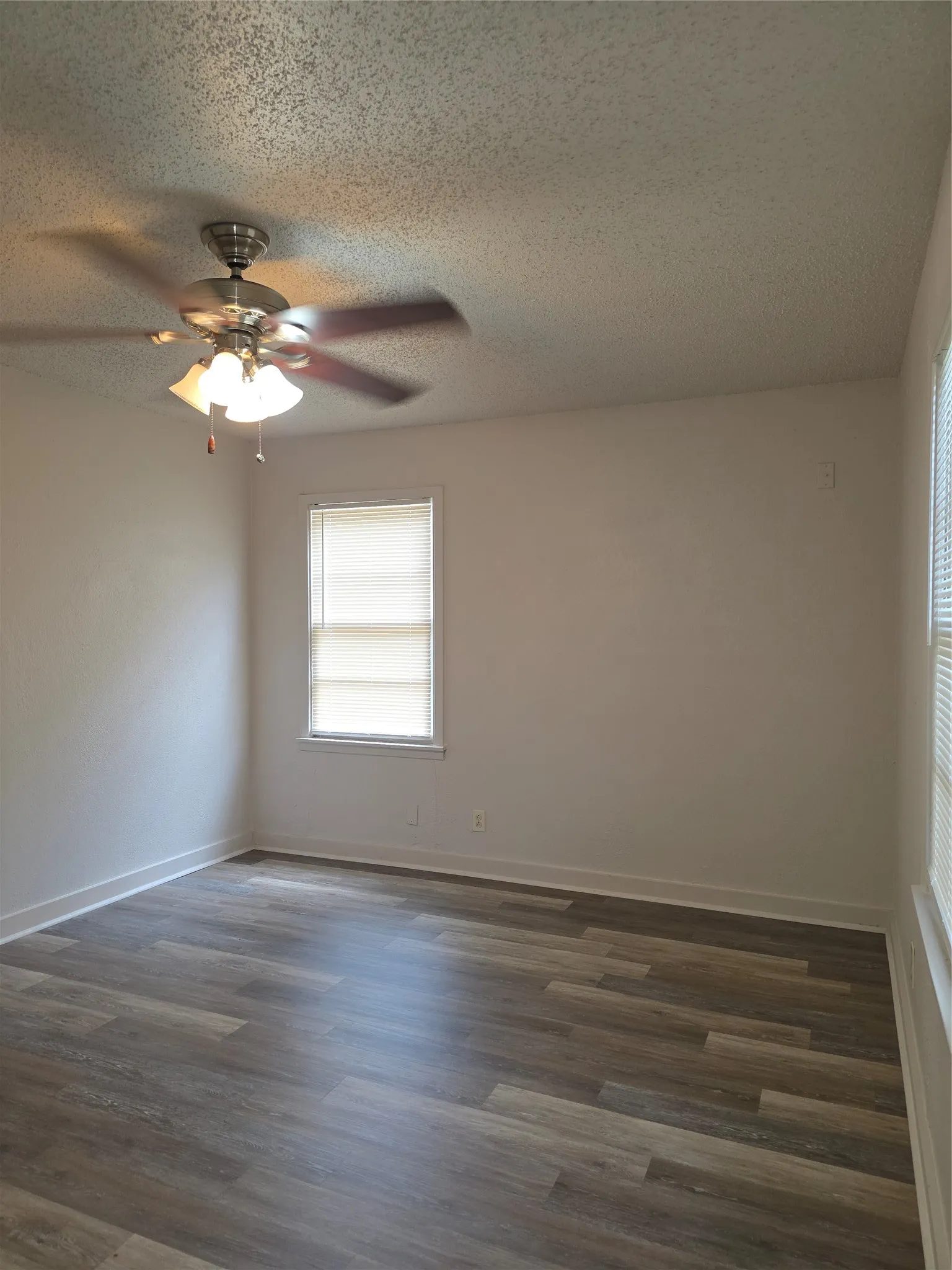 Room featuring wood-finish flooring, neutral wall tones, and white trim