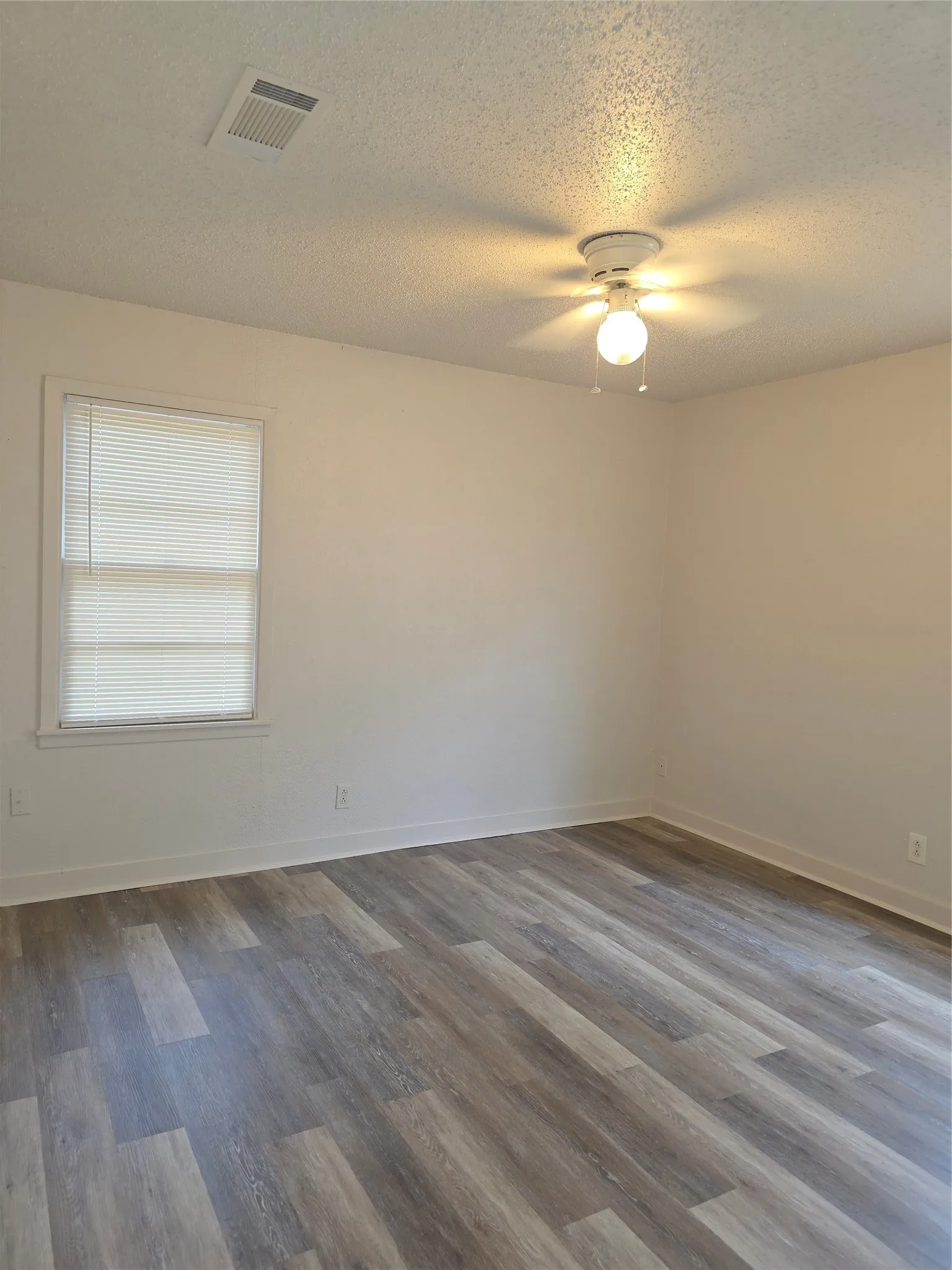 Interior room featuring wood-finish flooring, white baseboards, and neutral wall paint