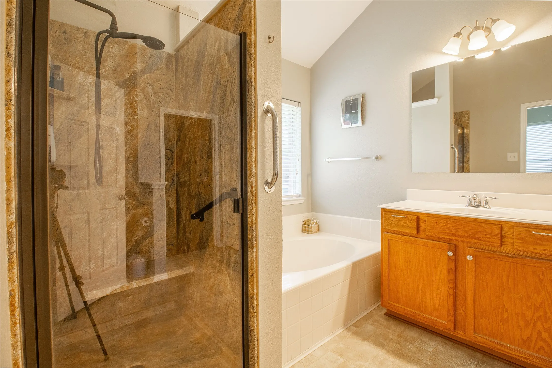 Glass-enclosed shower featuring natural stone walls and a built-in bench