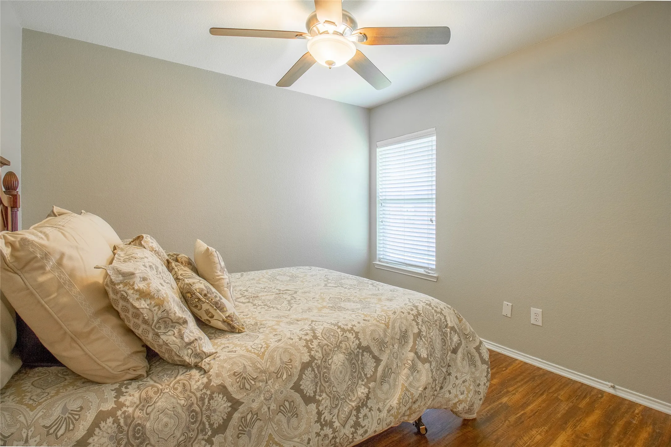 Room featuring wood-finish flooring, a ceiling fan with integrated lighting, and neutral wall tones