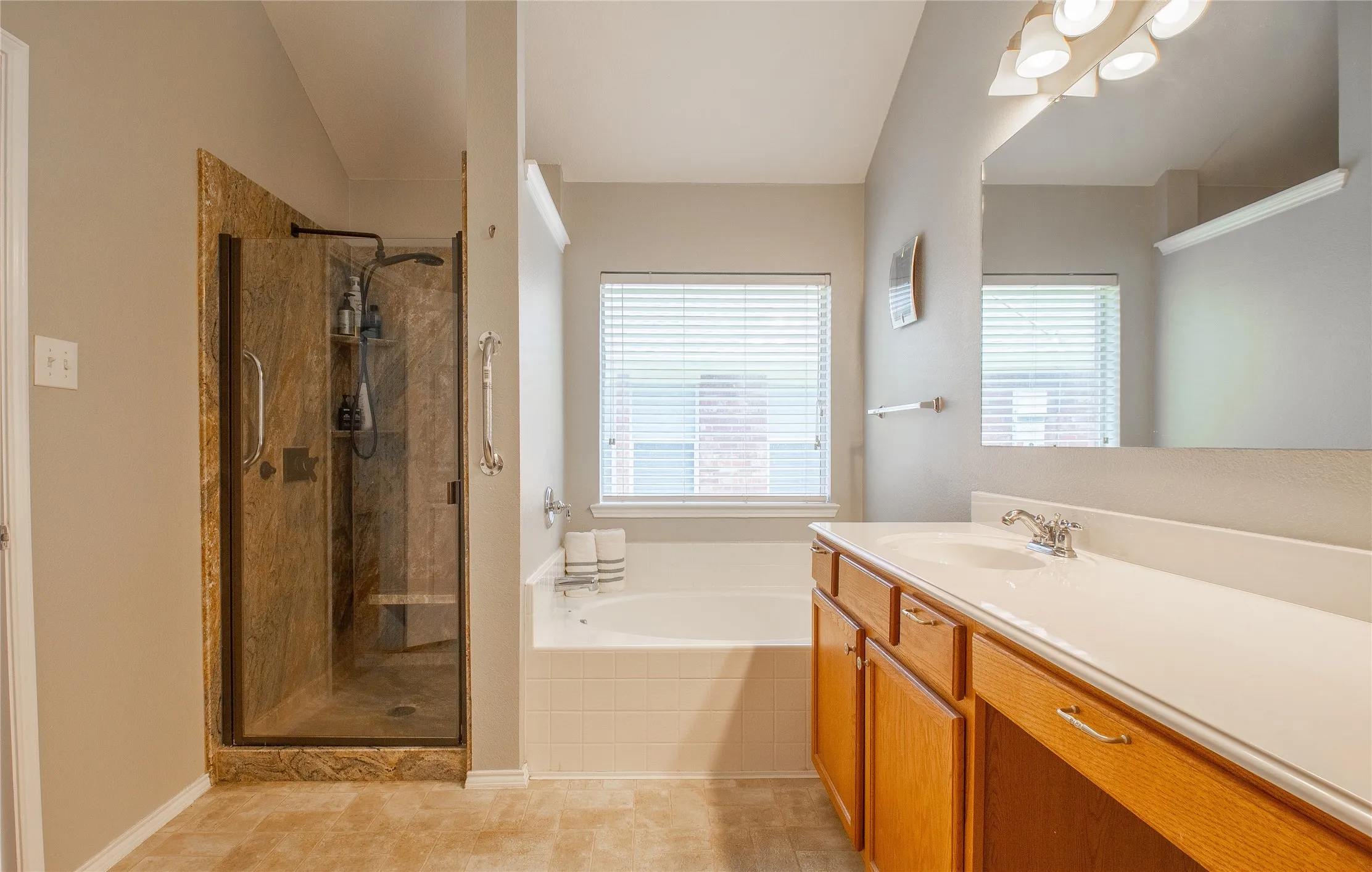 Spacious bathroom featuring a dual-sink vanity with light wood cabinetry and a large mirror