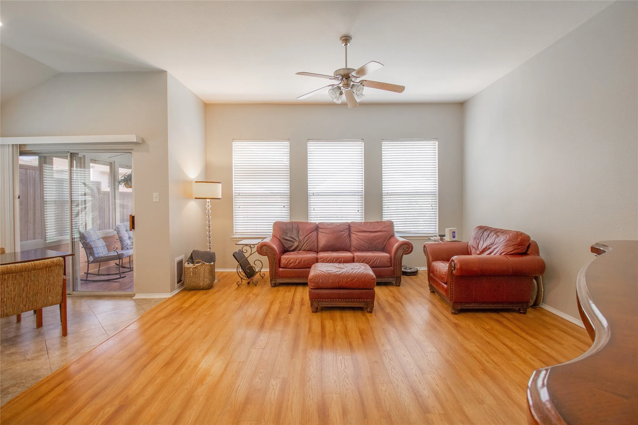 Living area featuring wood-finish flooring, a vaulted ceiling, and a ceiling fan with integrated lighting