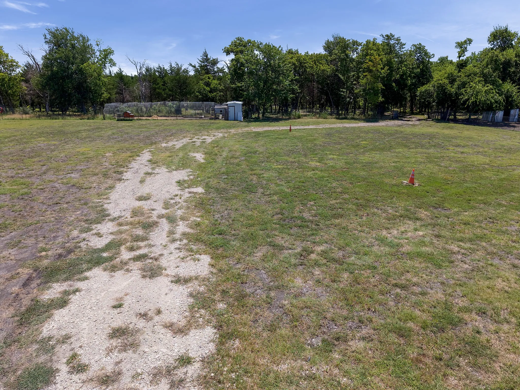 Expansive open lot with a gravel path leading towards a tree line