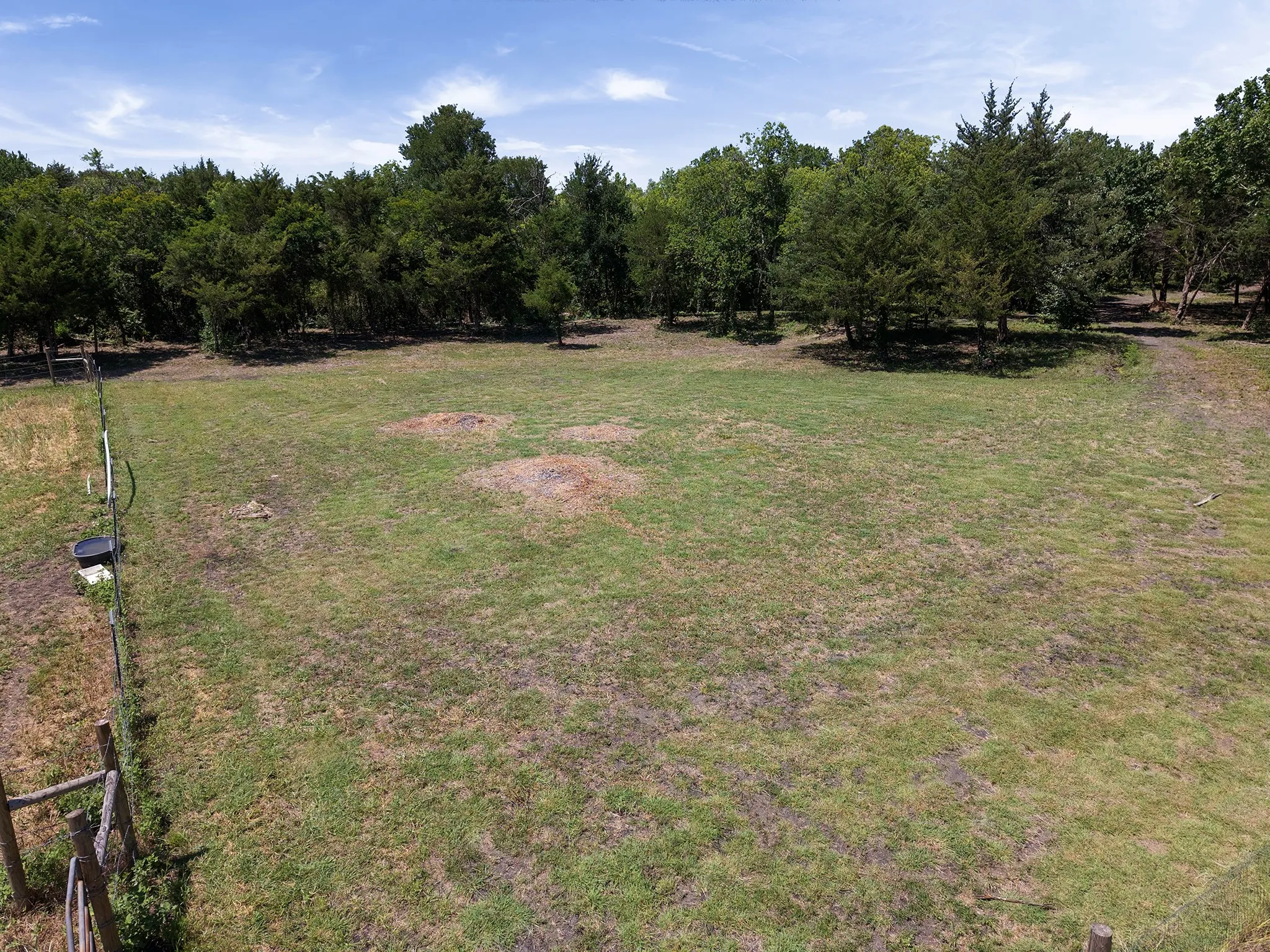 Expansive grassy lot bordered by mature trees