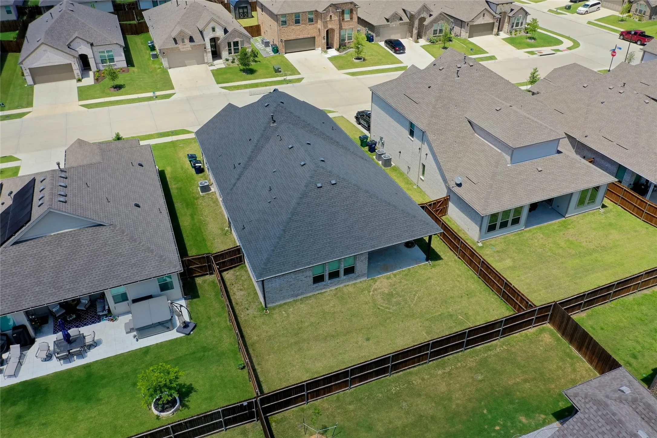 Expansive fenced backyard featuring a manicured lawn and a covered patio