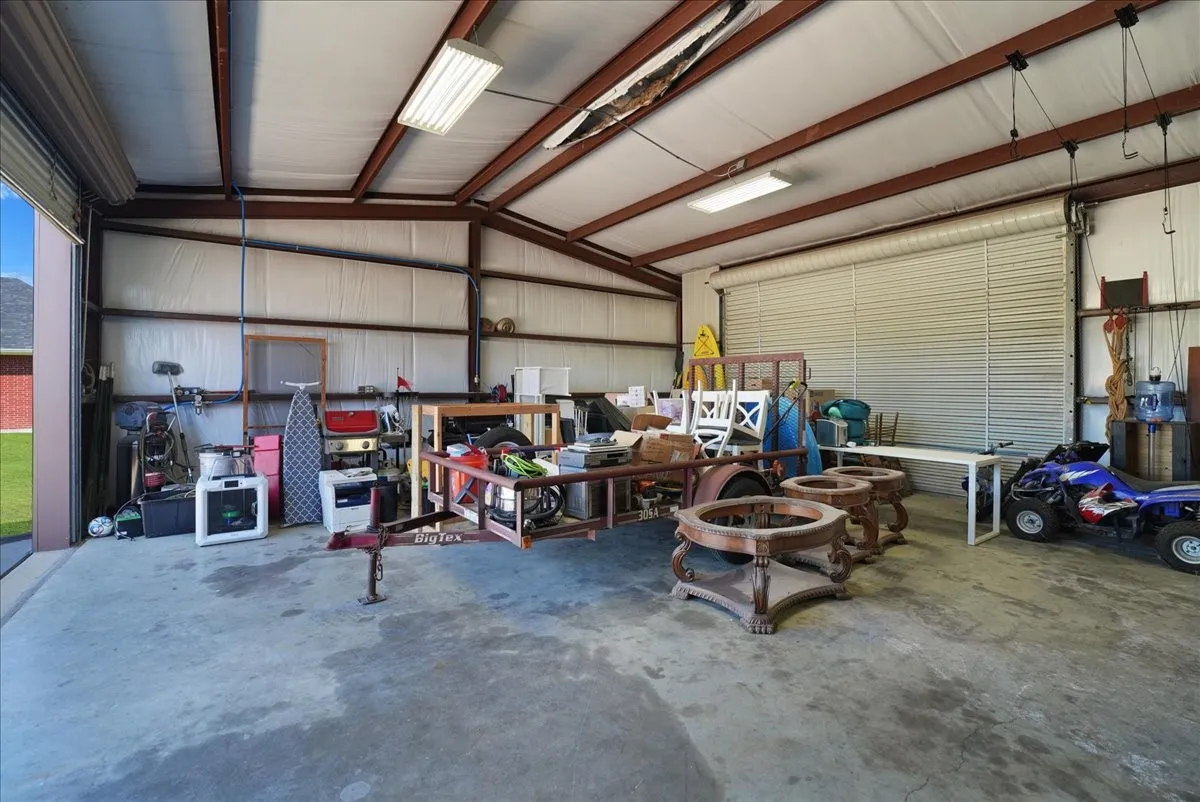 Spacious metal-frame building featuring a concrete slab, high ceilings with exposed beams, and fluorescent lighting
