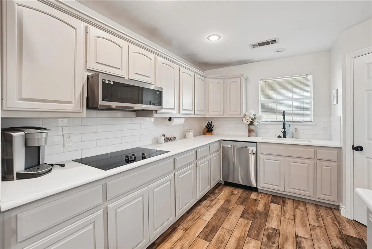 Modern kitchen featuring shaker-style cabinetry, white subway tile backsplash, and wood-finish flooring