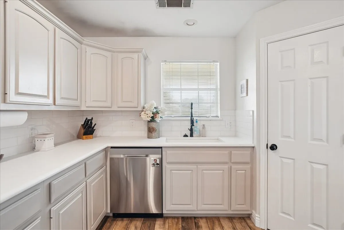 Kitchen featuring white upper cabinetry, gray lower cabinetry, white countertops, a subway tile backsplash, and wood-finish flooring