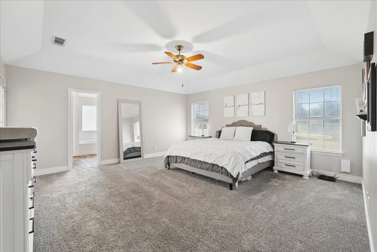 Spacious bedroom featuring plush gray carpeting and light-toned walls