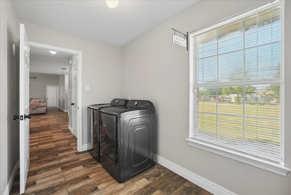 Utility area featuring wood-finish flooring, light gray wall paint, and a large window with white blinds