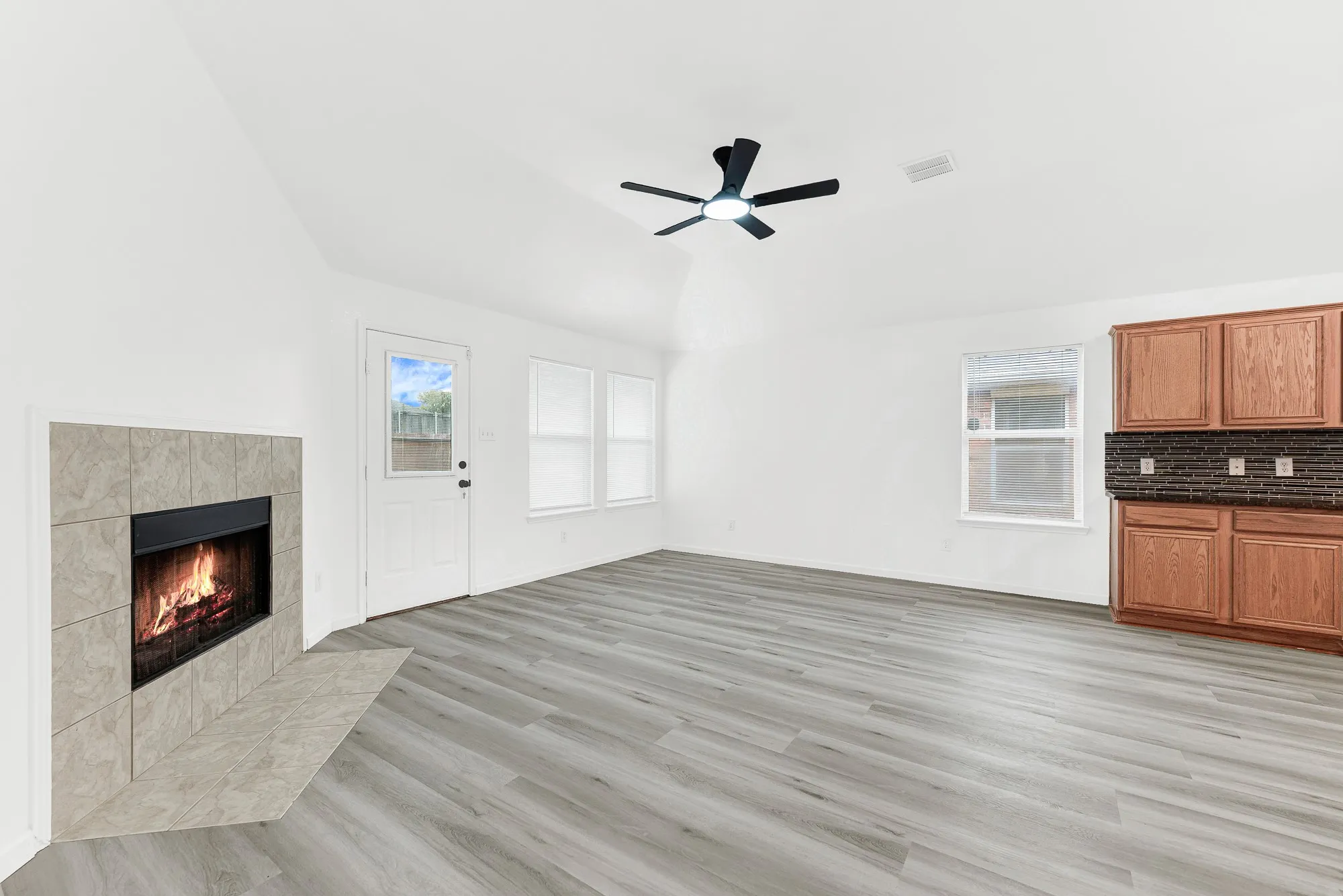 Vaulted ceiling with a ceiling fan over wood-finish flooring