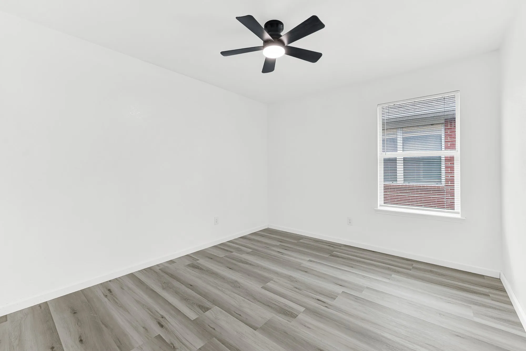 Room featuring wood-finish flooring, a ceiling fan with integrated lighting, and a window with blinds