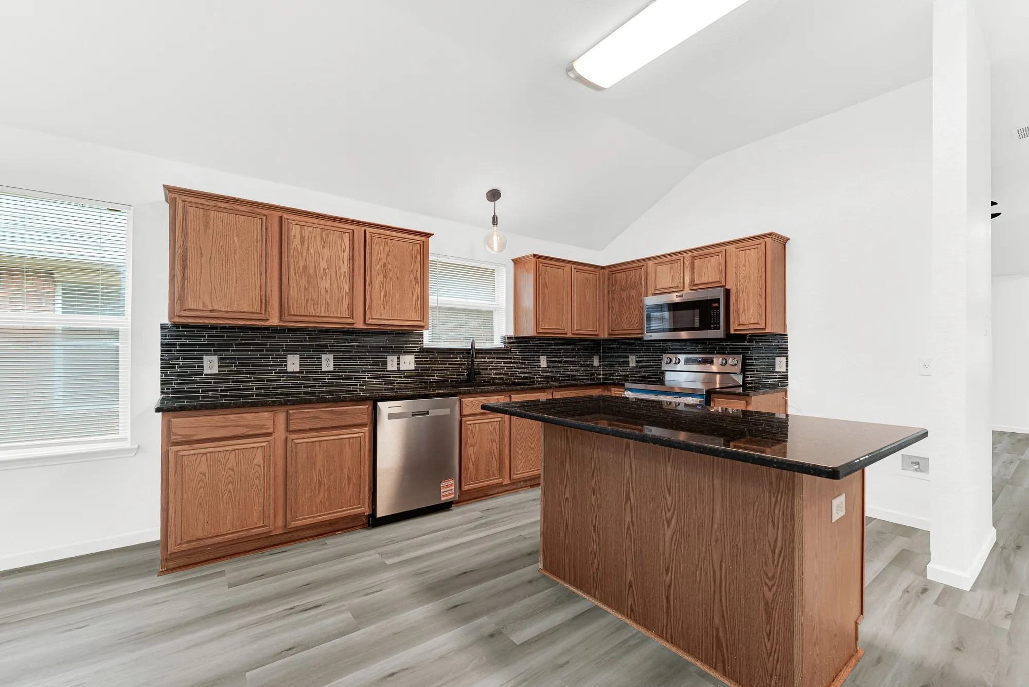 Kitchen featuring wood cabinetry, dark countertops, and a full suite of stainless steel appliances