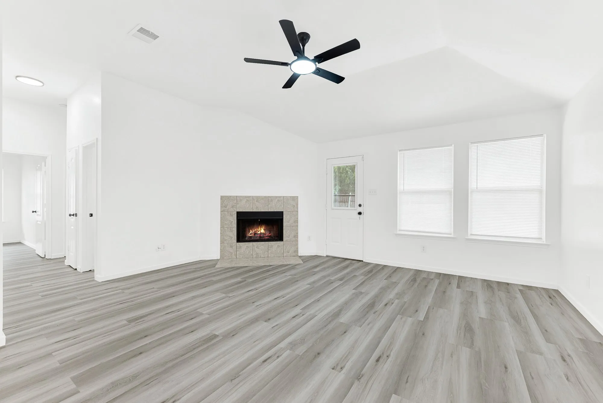 Spacious room featuring vaulted ceilings, a contemporary ceiling fan, and light wood-finish flooring