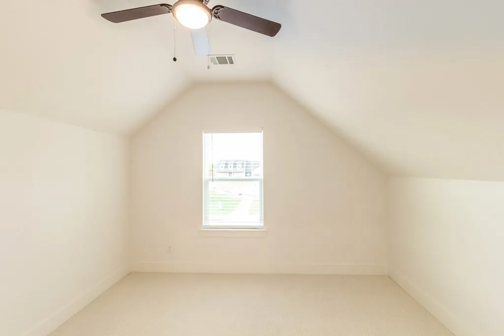 Vaulted ceiling with a ceiling fan and integrated lighting, single window with blinds, and neutral carpeting