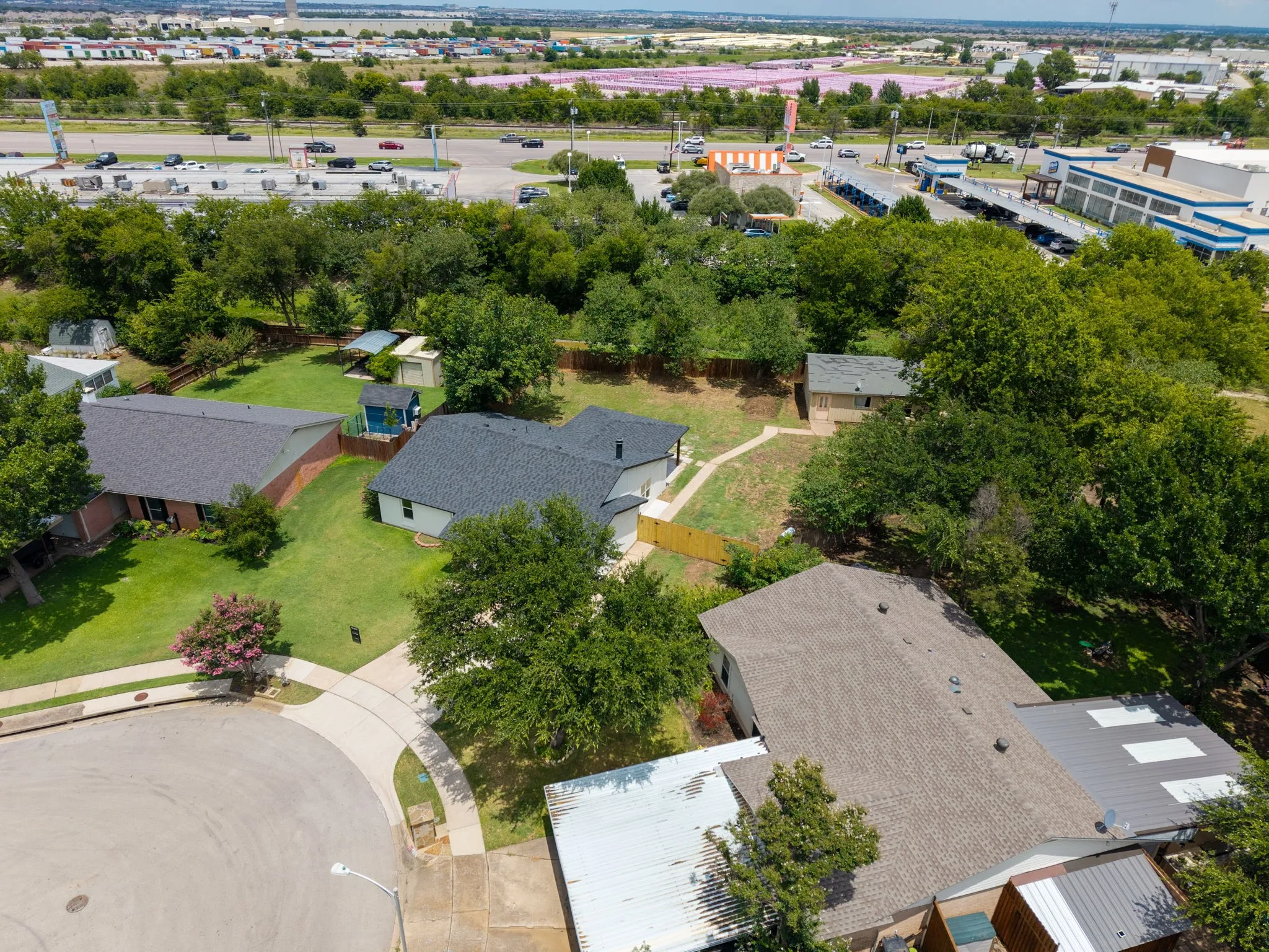Aerial view highlighting a residential street with multiple properties featuring mature landscaping and fenced yards
