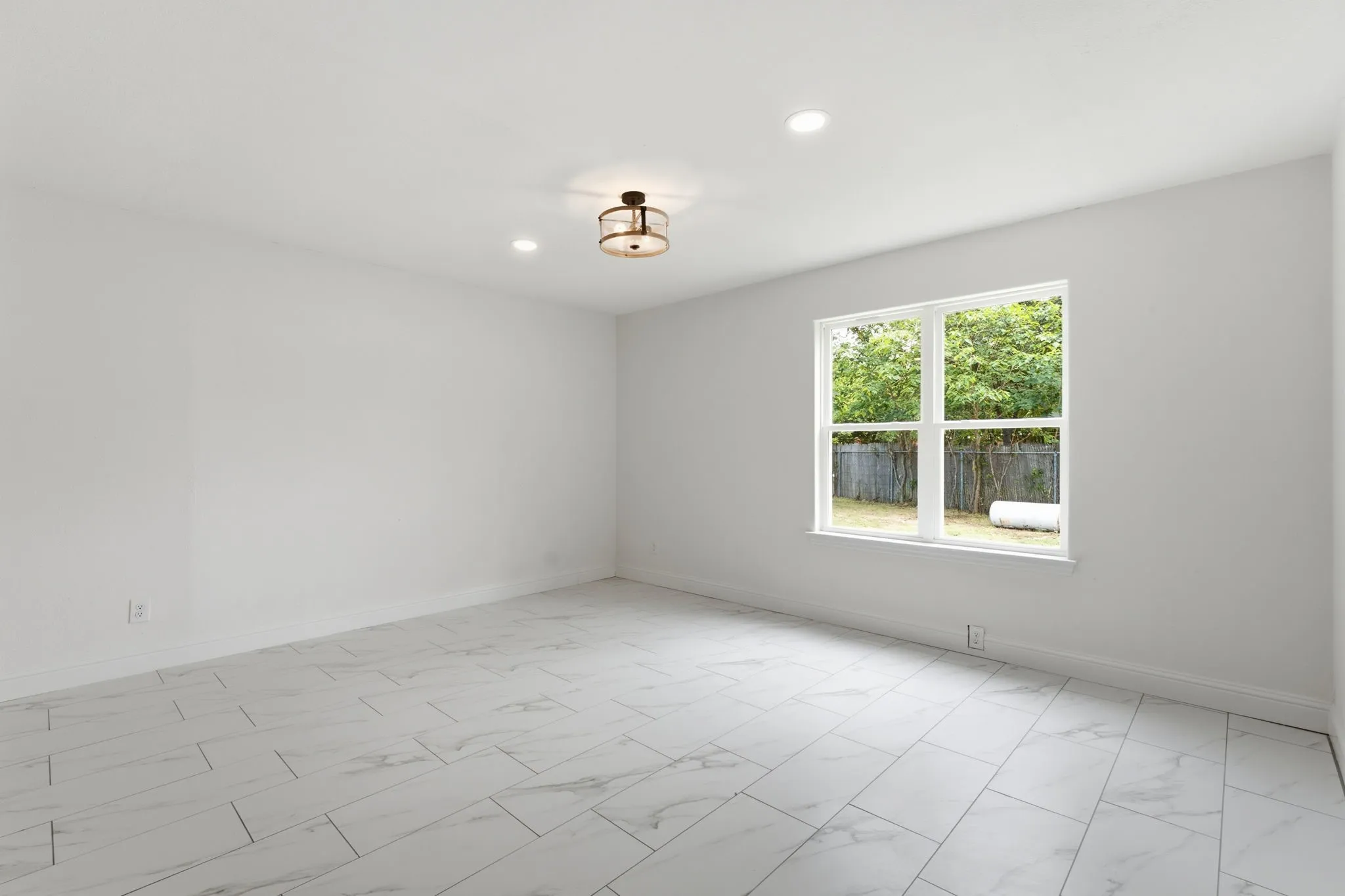 Spacious room featuring white walls, large window, sleek tile flooring, recessed lighting, and a modern ceiling fixture