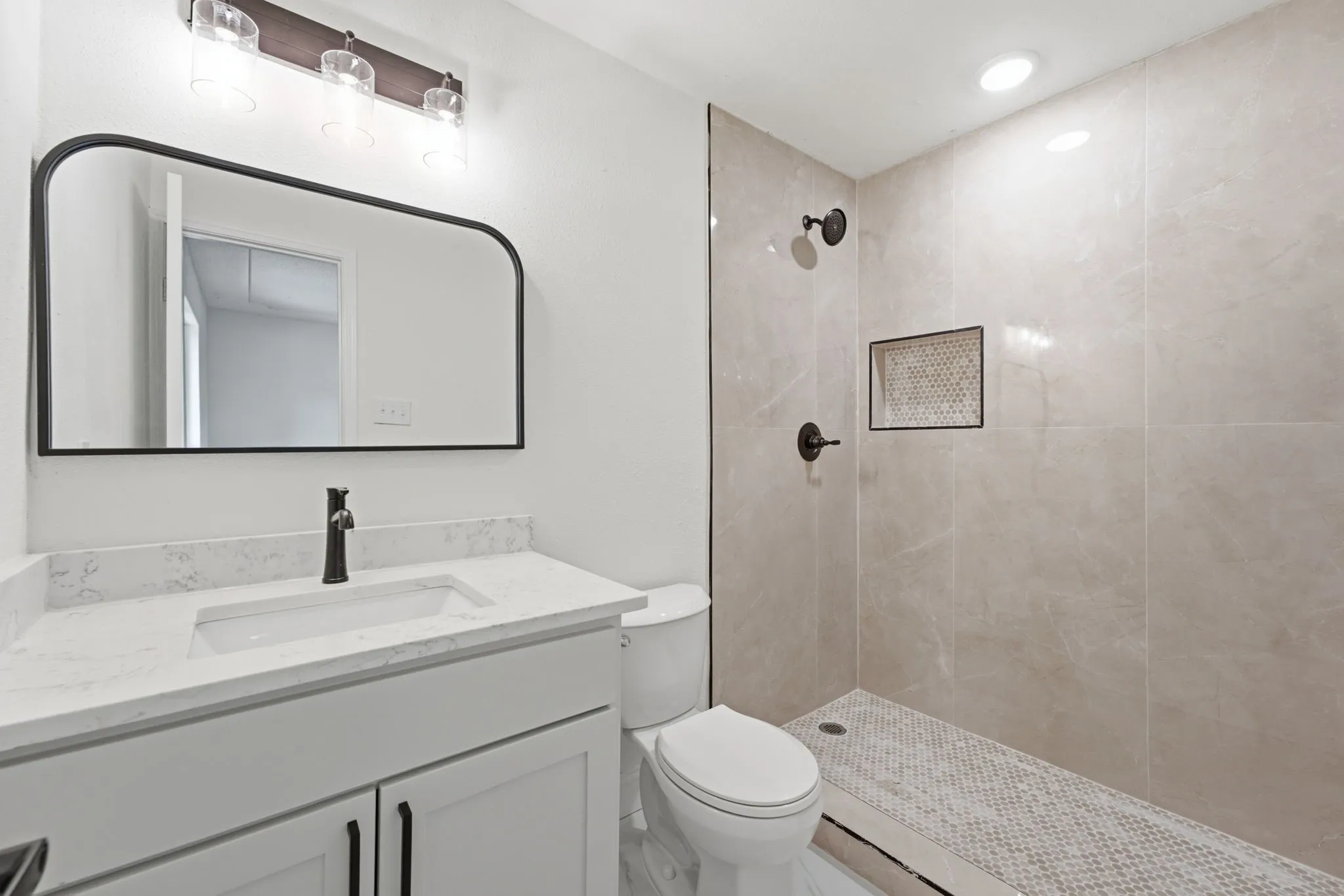 Bathroom featuring a white vanity with a quartz-finish countertop, a single basin sink, and a matte black faucet
