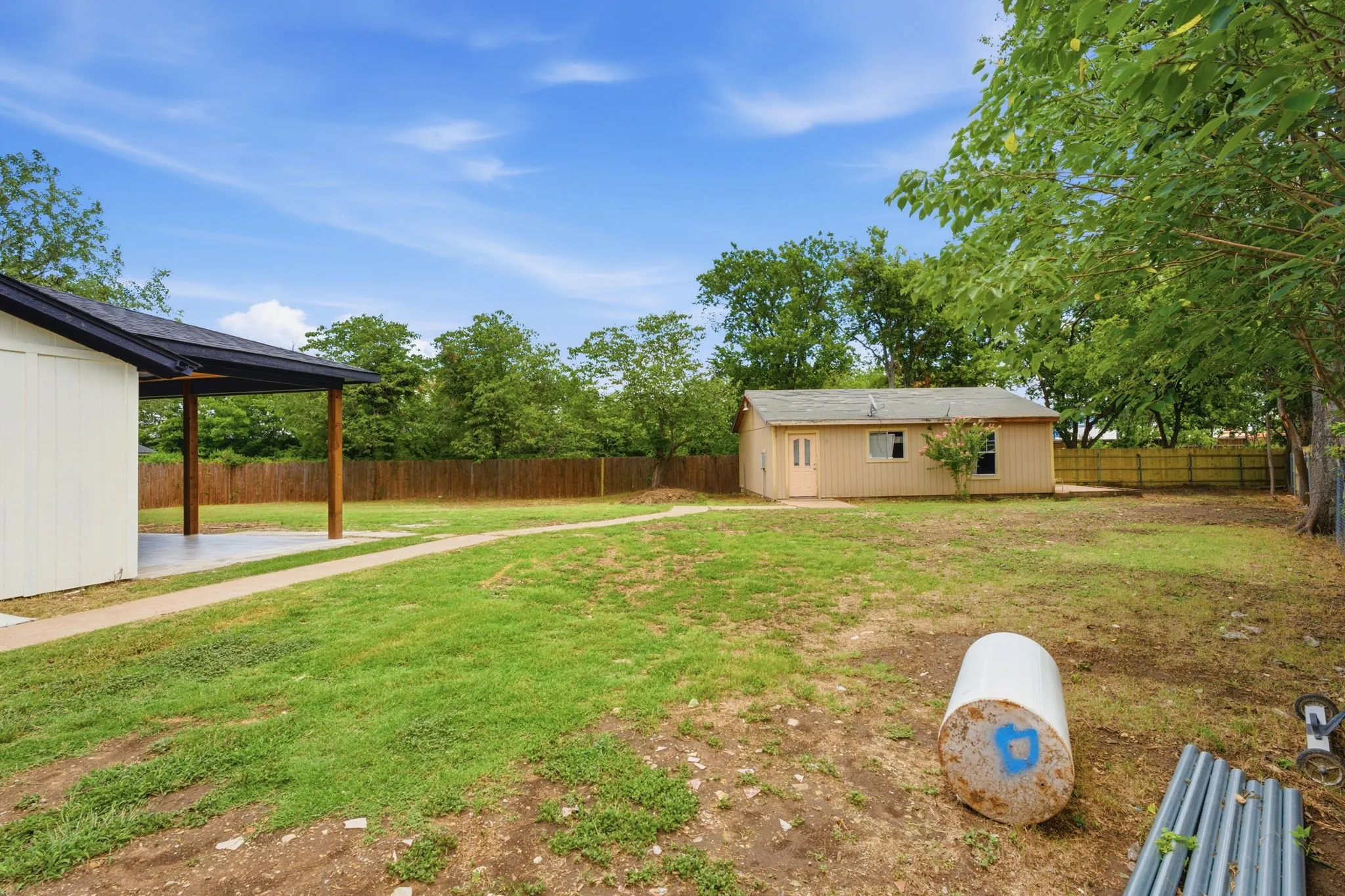 Expansive backyard featuring a covered patio, a separate auxiliary building, and a wood privacy fence