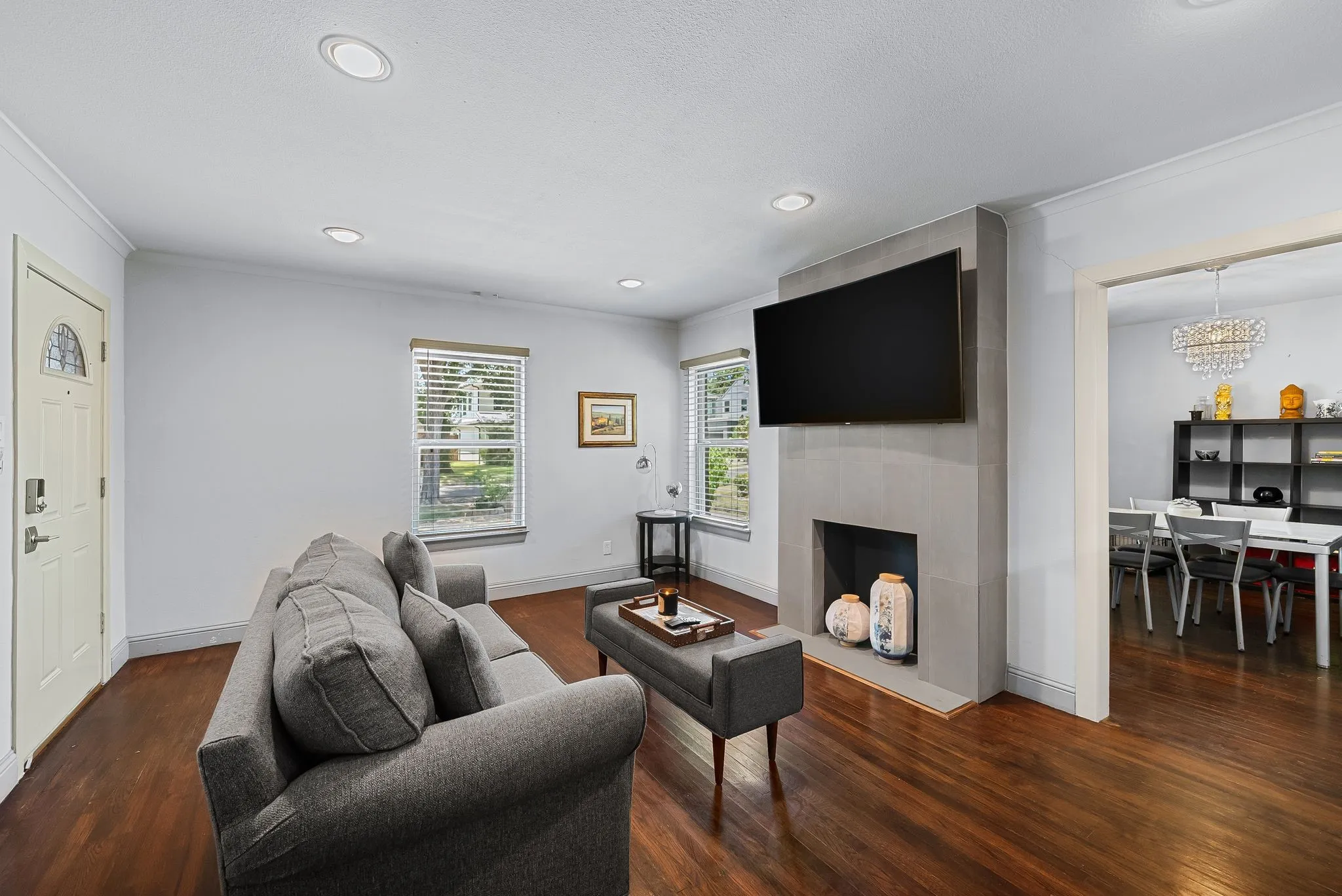 Living area featuring a floor-to-ceiling fireplace with a mounted display, hardwood flooring, and recessed lighting