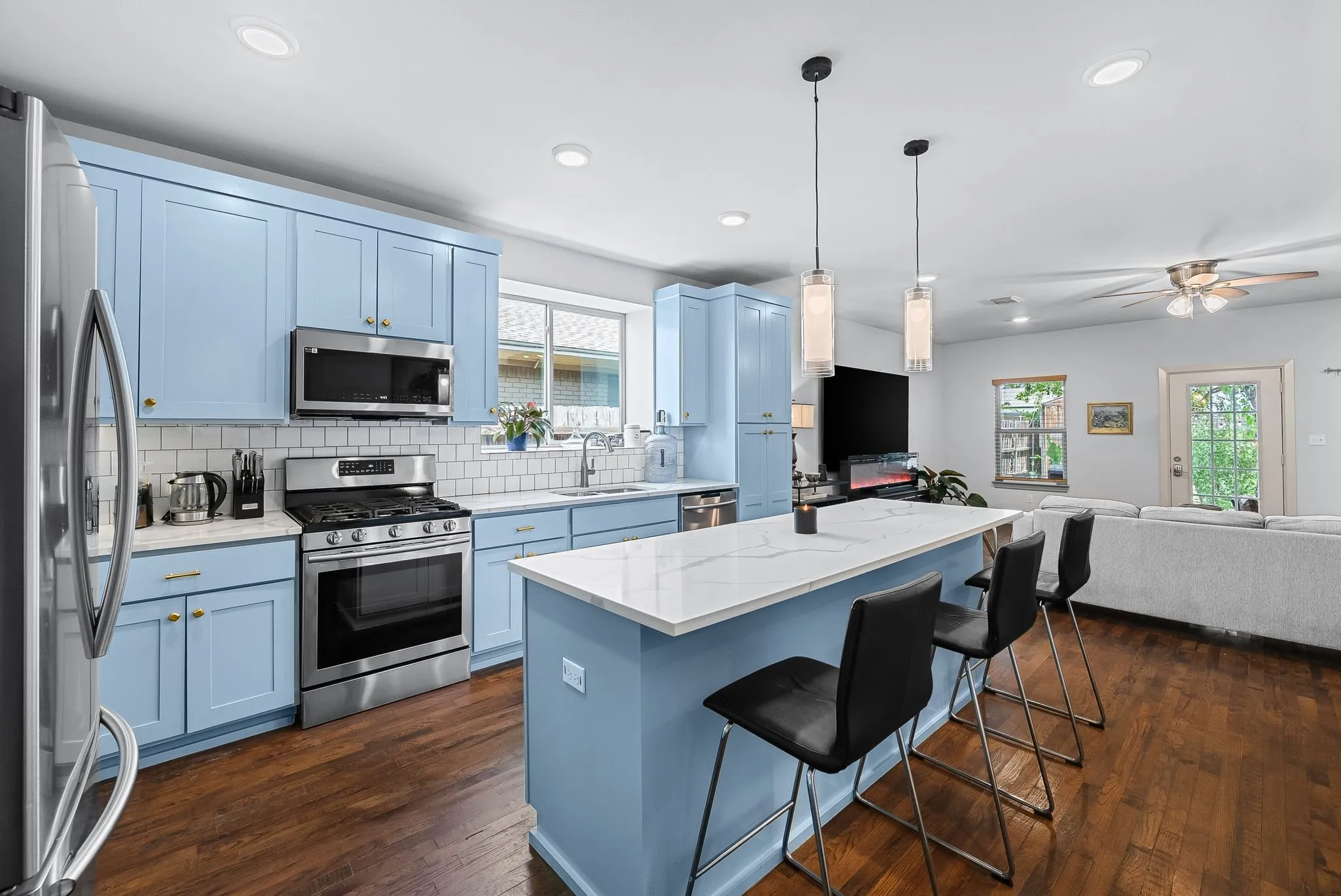 Modern kitchen featuring light blue cabinetry, stainless steel appliances, and a center island with pendant lighting