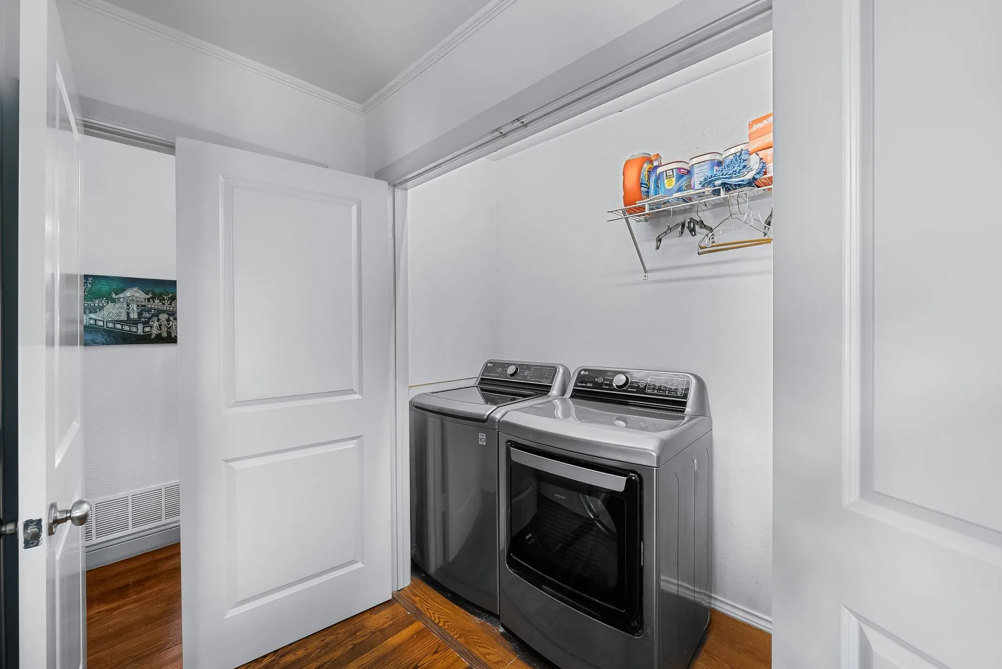 Dedicated laundry area featuring wood flooring and a wire shelving unit