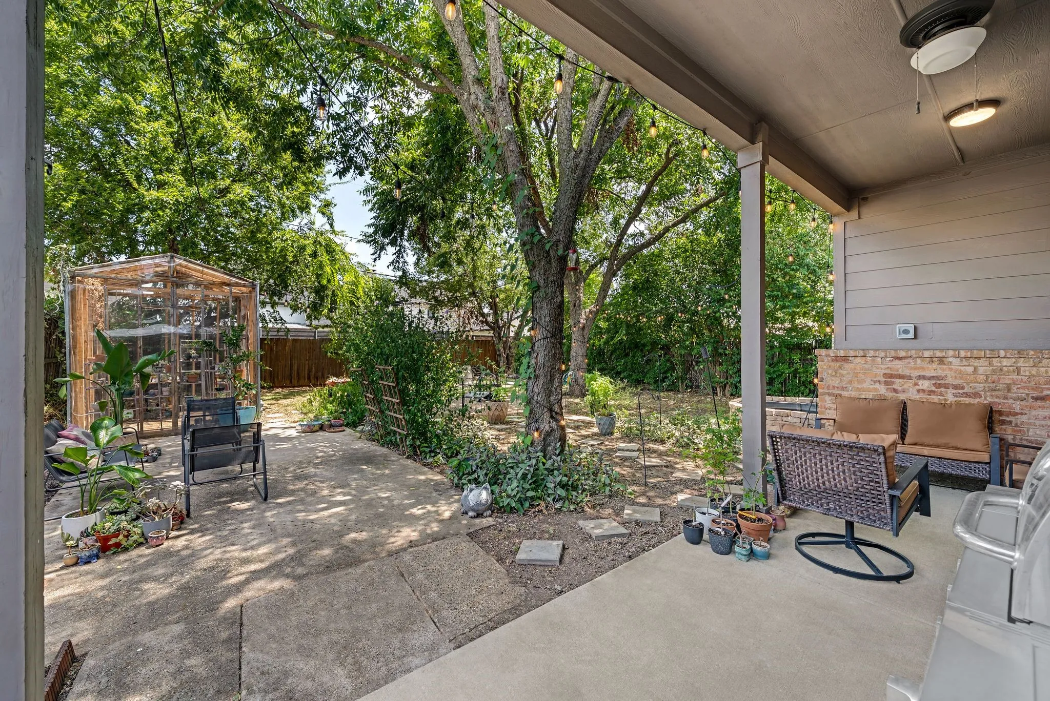 Covered patio featuring a brick accent wall and a ceiling fan