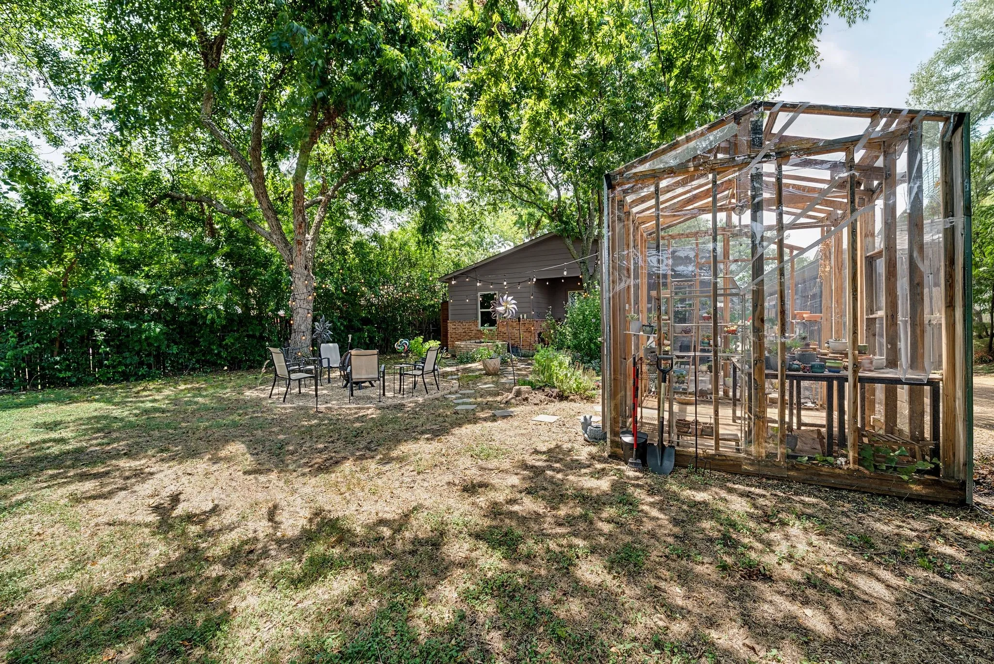 Spacious yard featuring a custom-built greenhouse with wood framing and transparent paneling