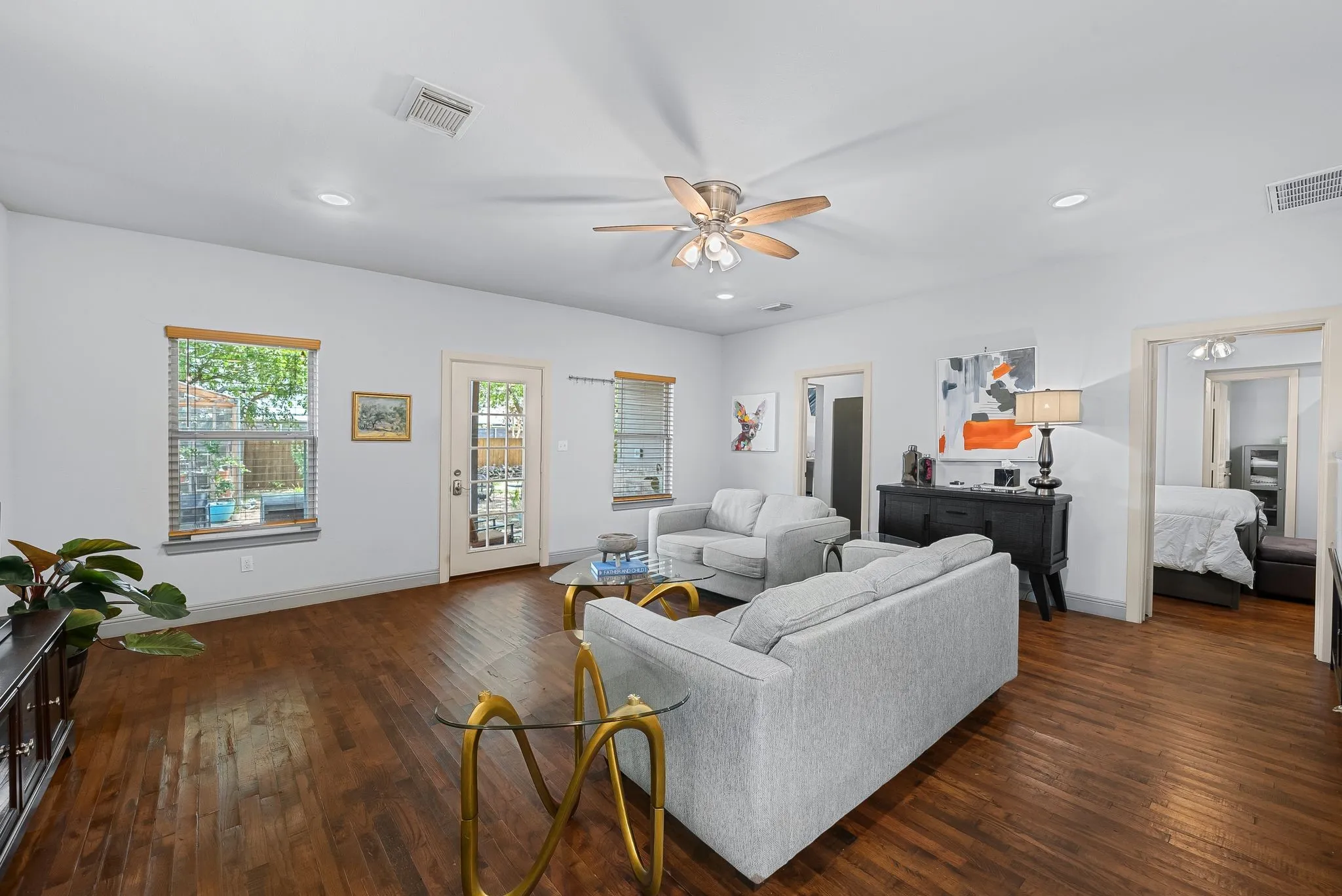 Spacious living area featuring wood-finish flooring, recessed lighting, a ceiling fan, and multiple windows