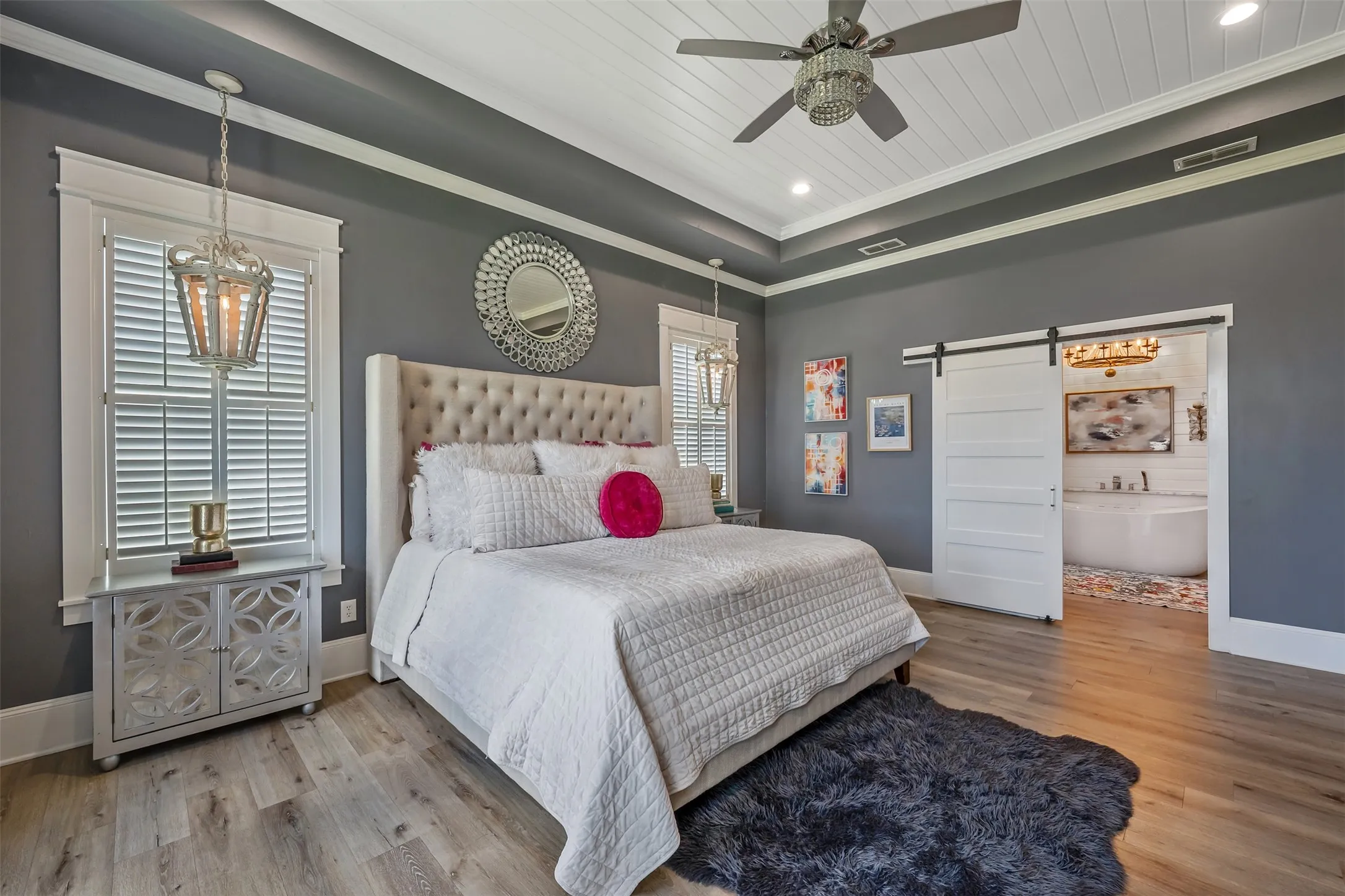 Spacious bedroom featuring wood-finish flooring, a tray ceiling with shiplap detailing, and a modern ceiling fan