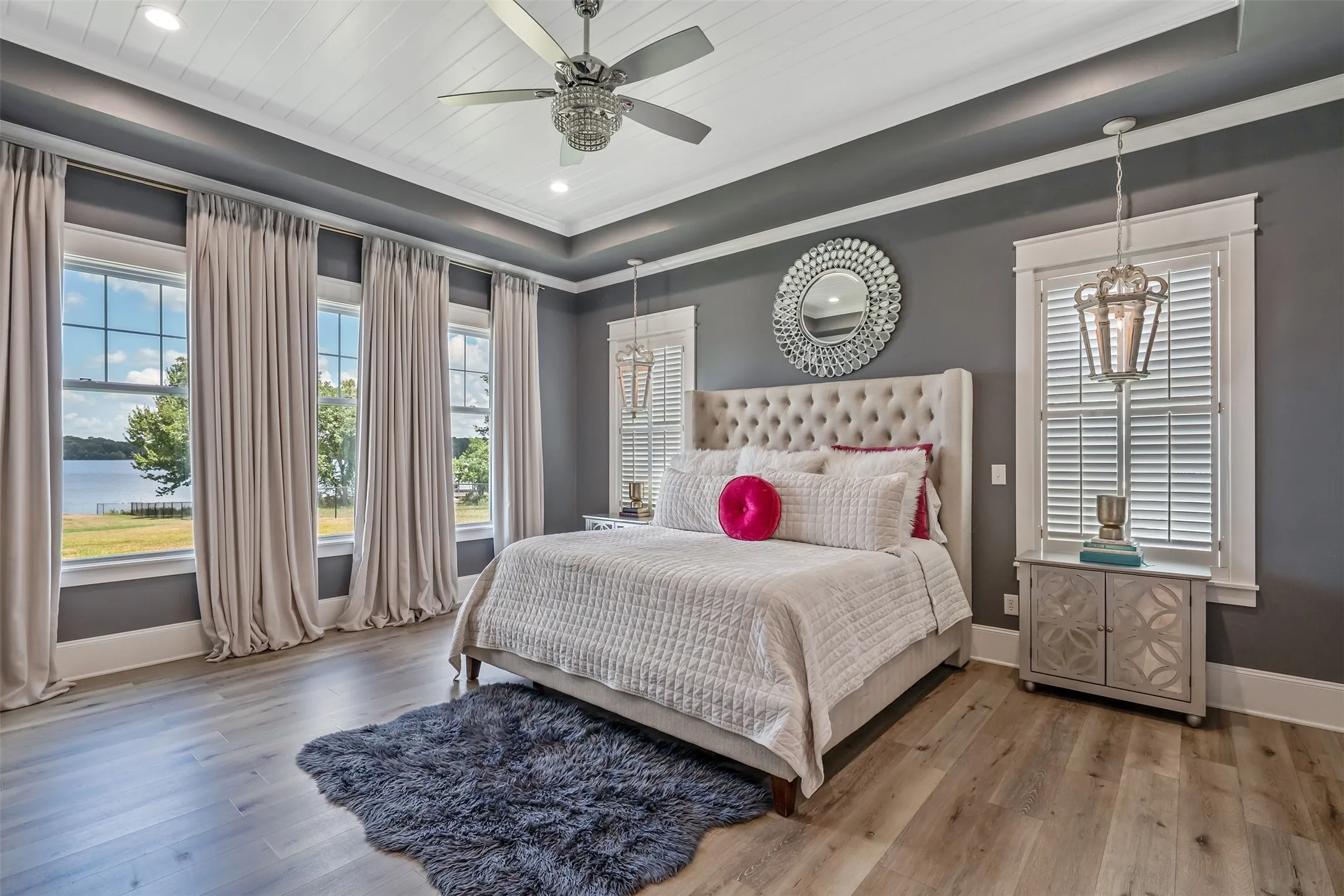 Spacious room featuring multiple large windows with water scenery, wood-finish flooring, and a tray ceiling with recessed lighting