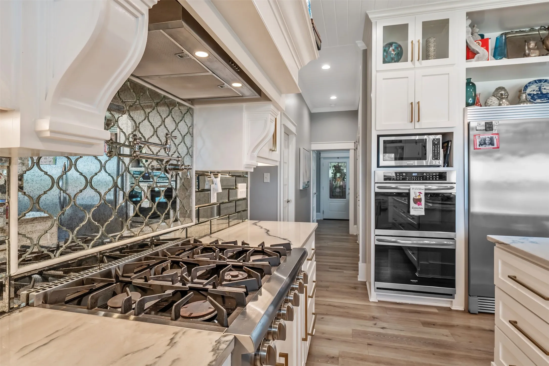Gourmet kitchen with a professional-grade stainless steel range, custom range hood, and a decorative mirrored tile backsplash