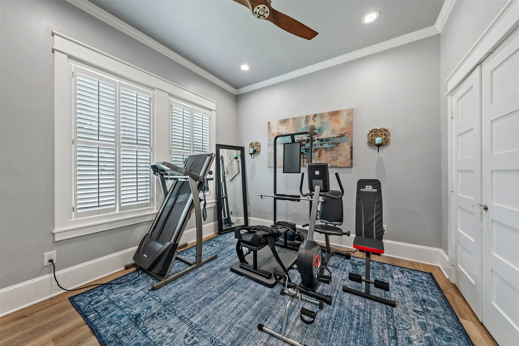 Room featuring wood-finish flooring, plantation shutters, crown molding, and recessed lighting