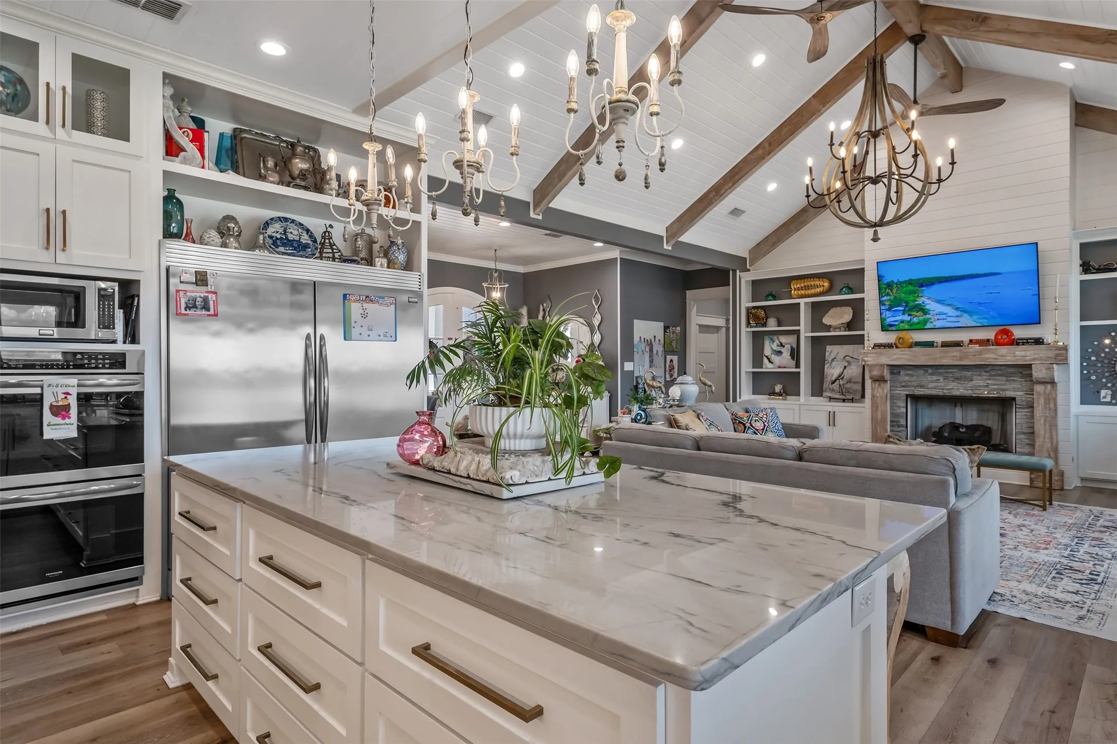 Expansive kitchen island with a stone-finish countertop, white cabinetry, and bronze-tone hardware