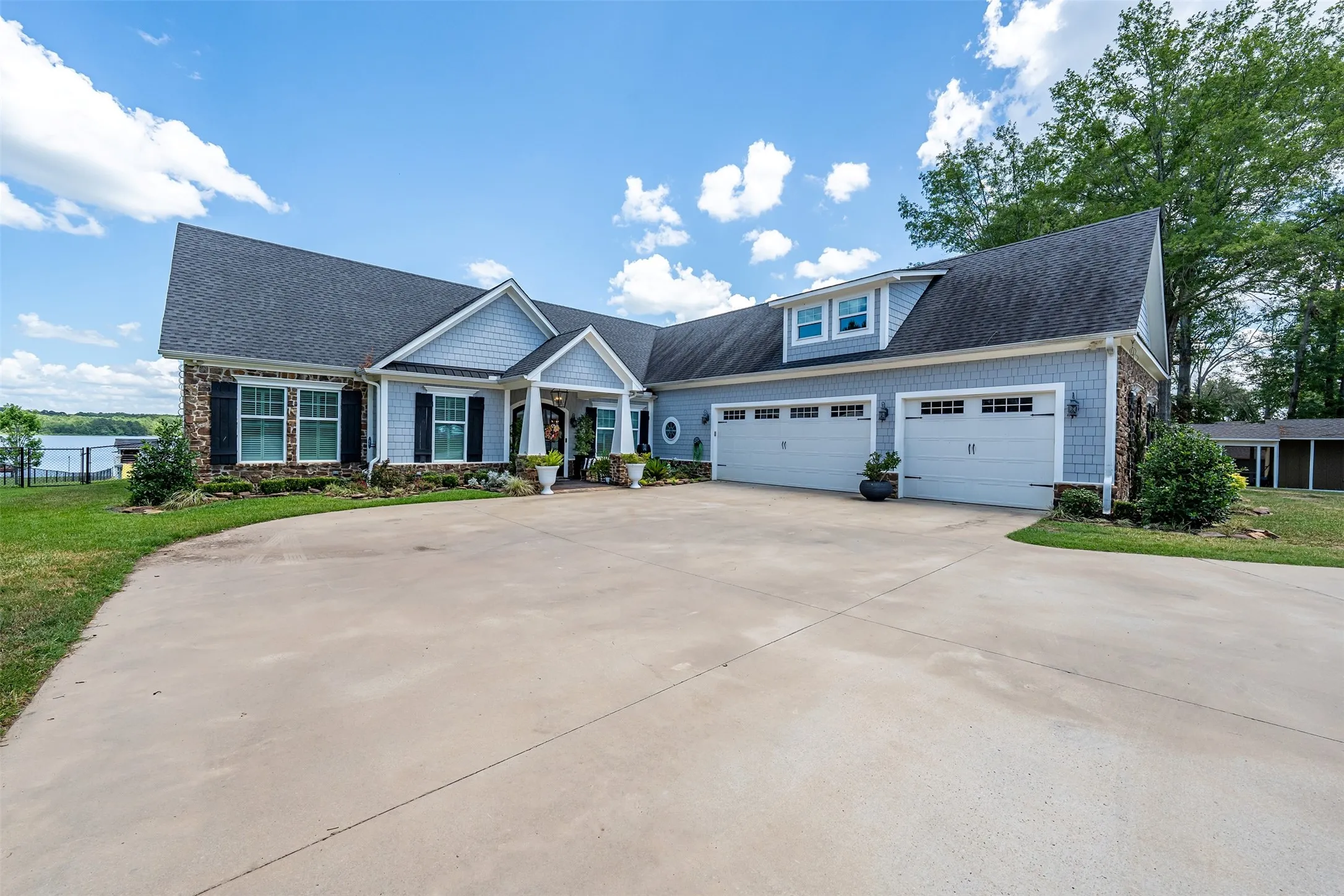 Two-story residence featuring a gray shingle roof, light blue siding, and stone accents