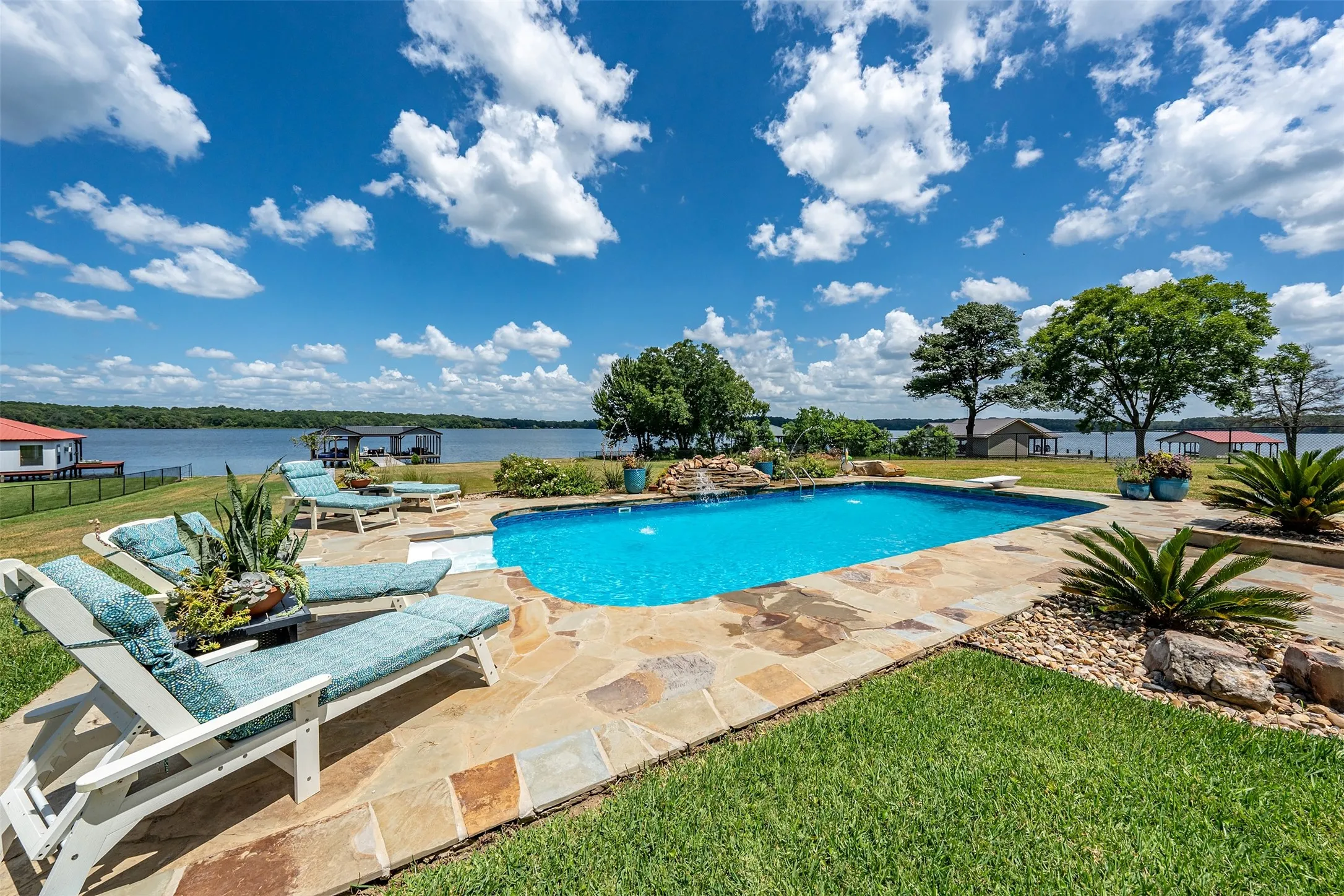 In-ground swimming pool with flagstone surround, rock landscaping, and water feature