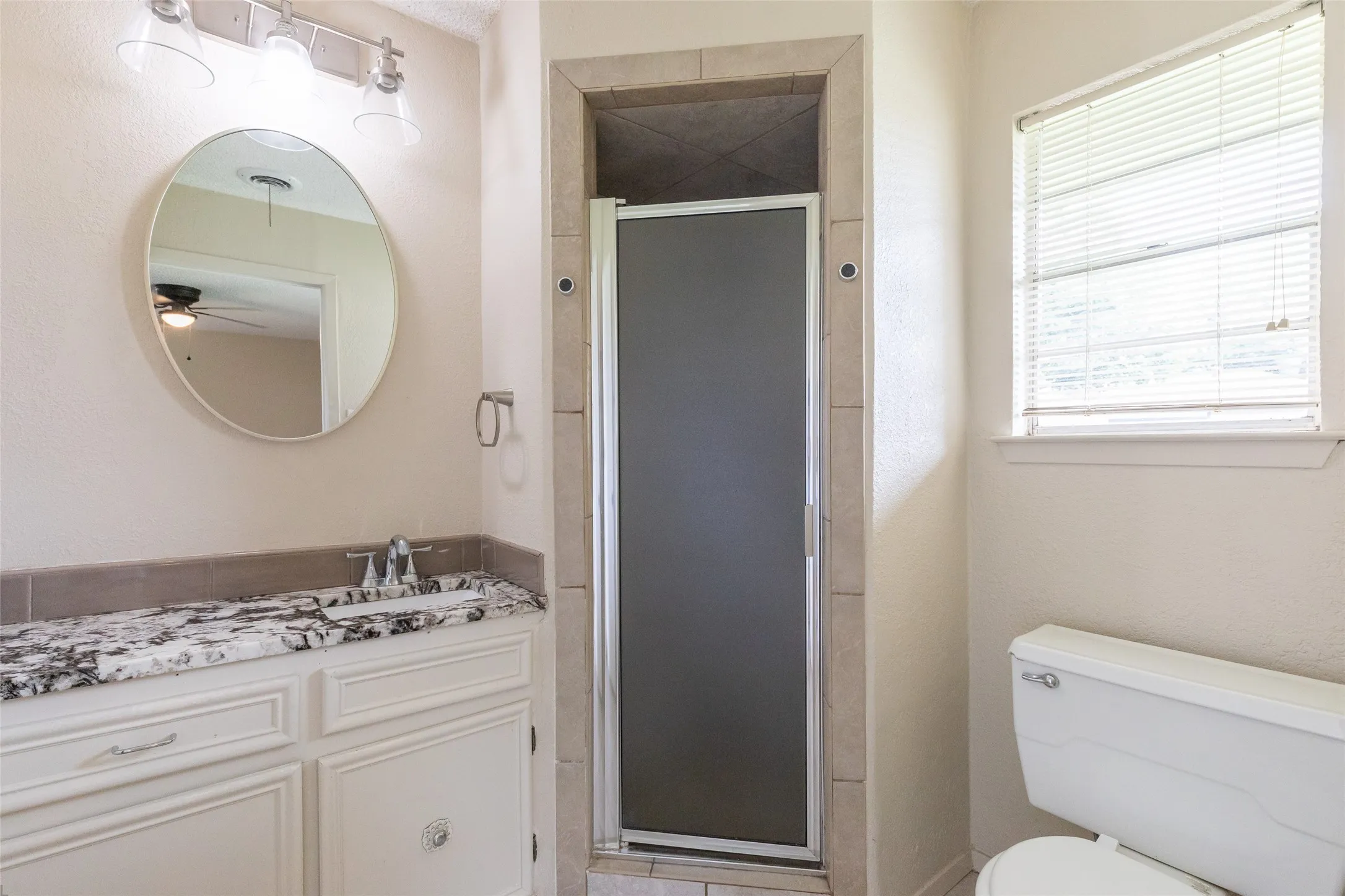 Bathroom featuring a white vanity with a patterned countertop, undermount sink, and chrome faucet