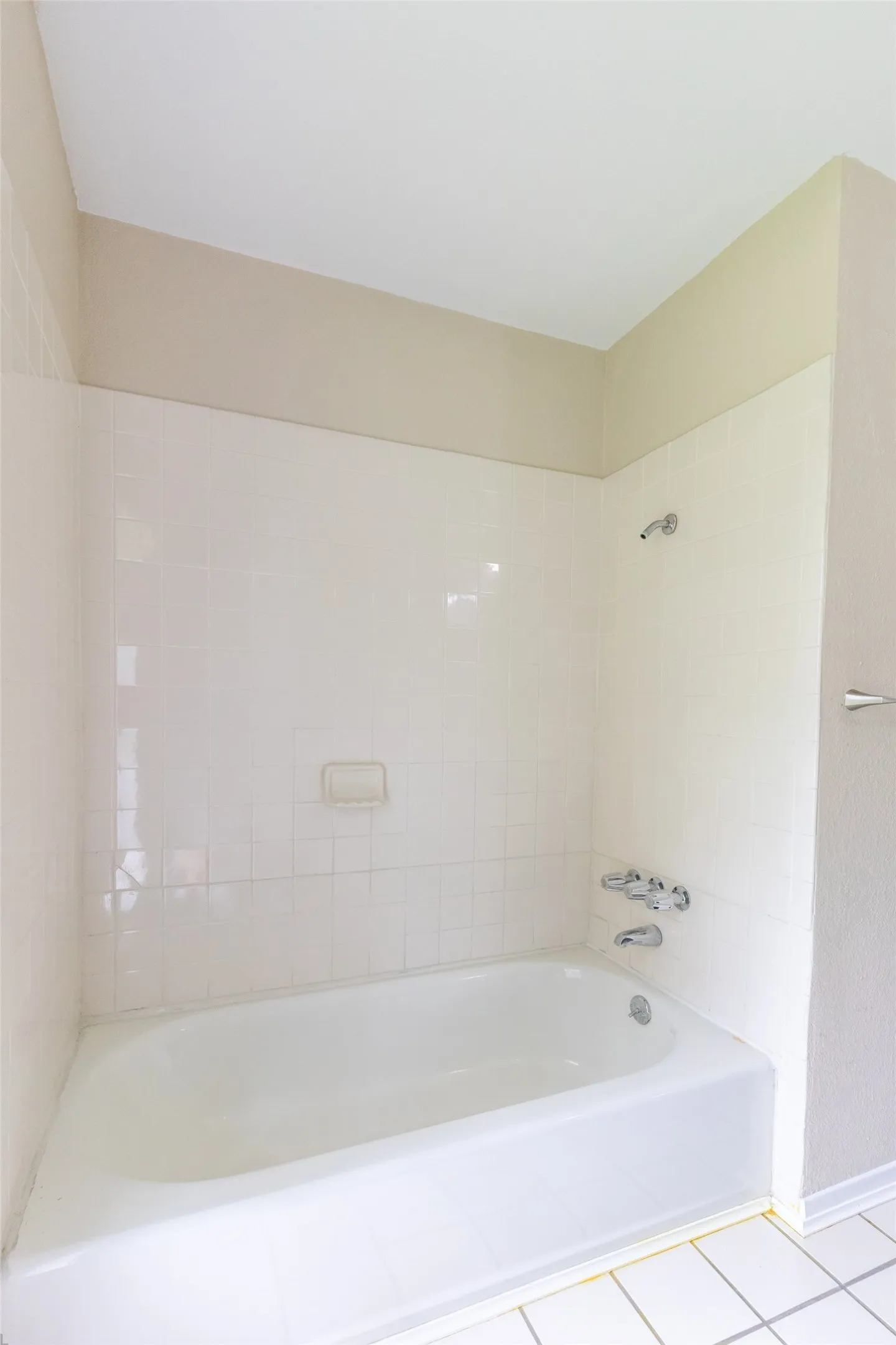 White bathtub with chrome fixtures, surrounded by white subway tile walls