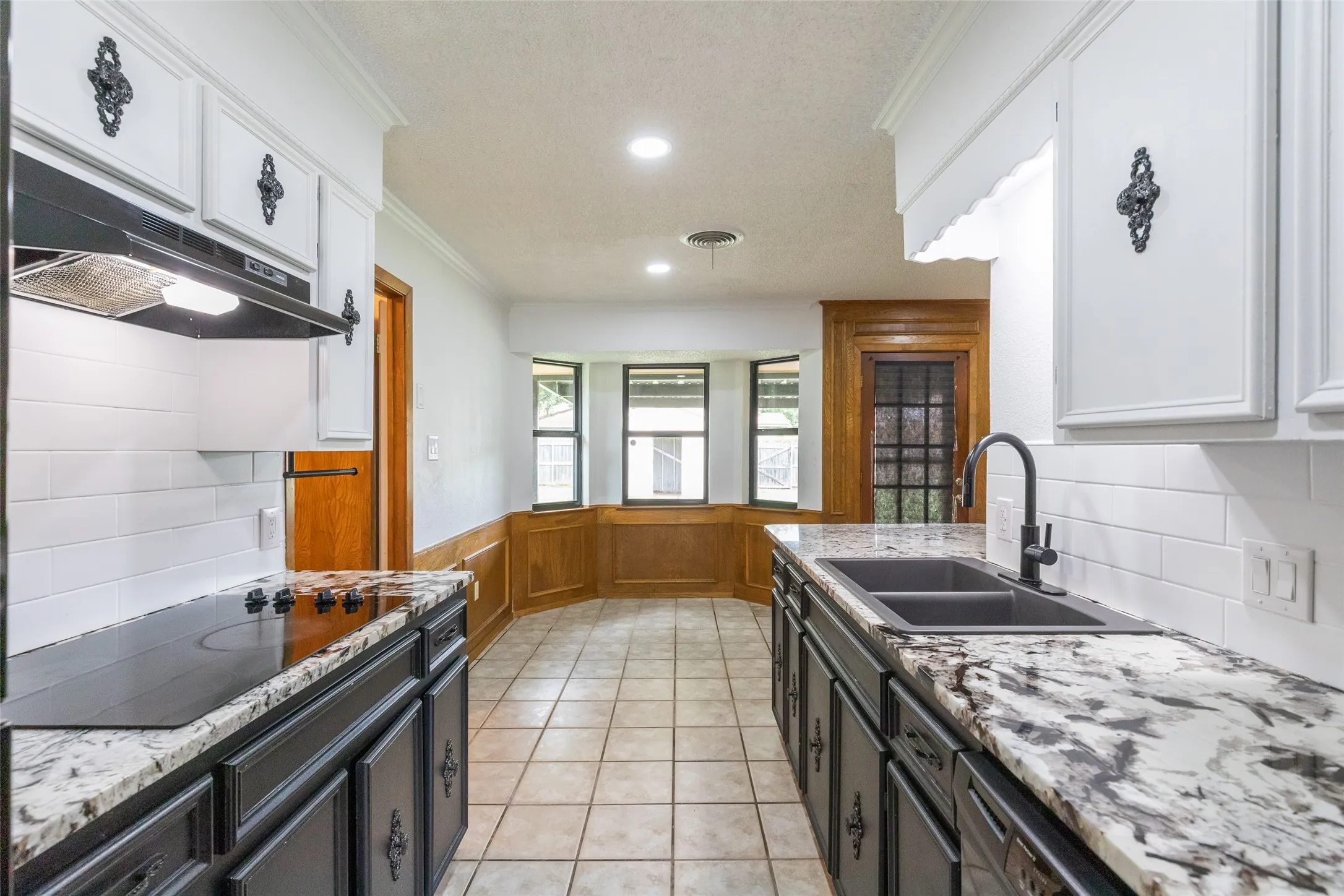 Kitchen featuring granite countertops, a black ceramic cooktop, and a double basin sink with a matte black faucet
