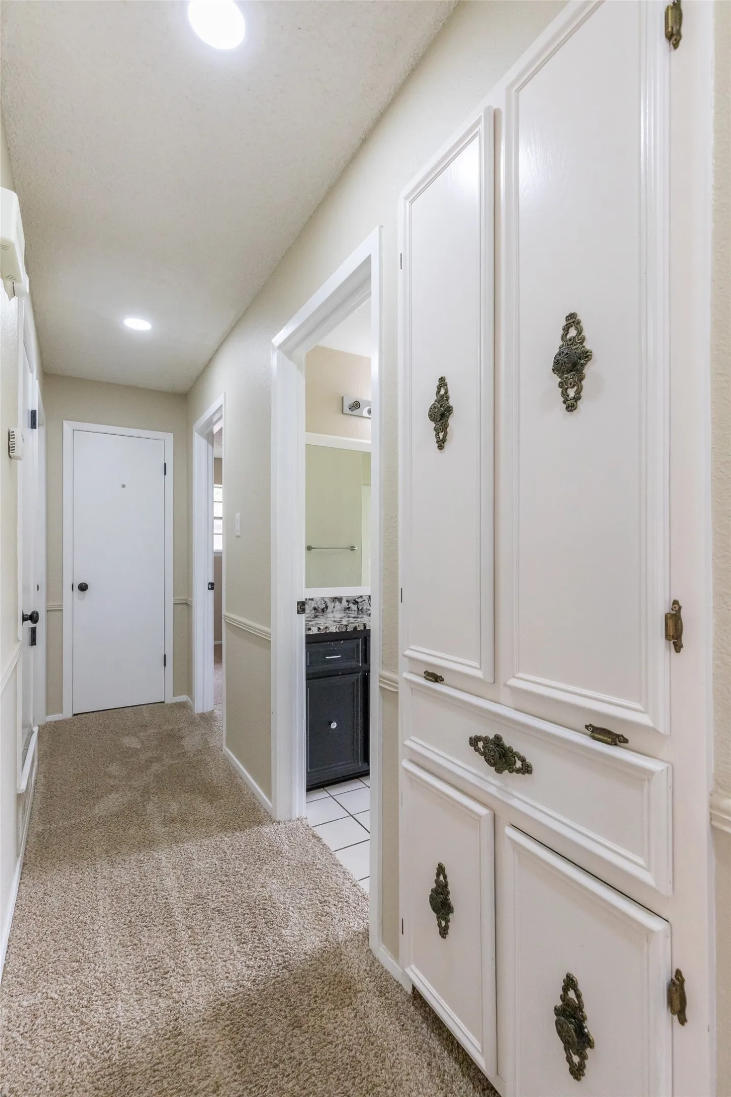 Hallway featuring built-in white cabinetry with decorative brass hardware