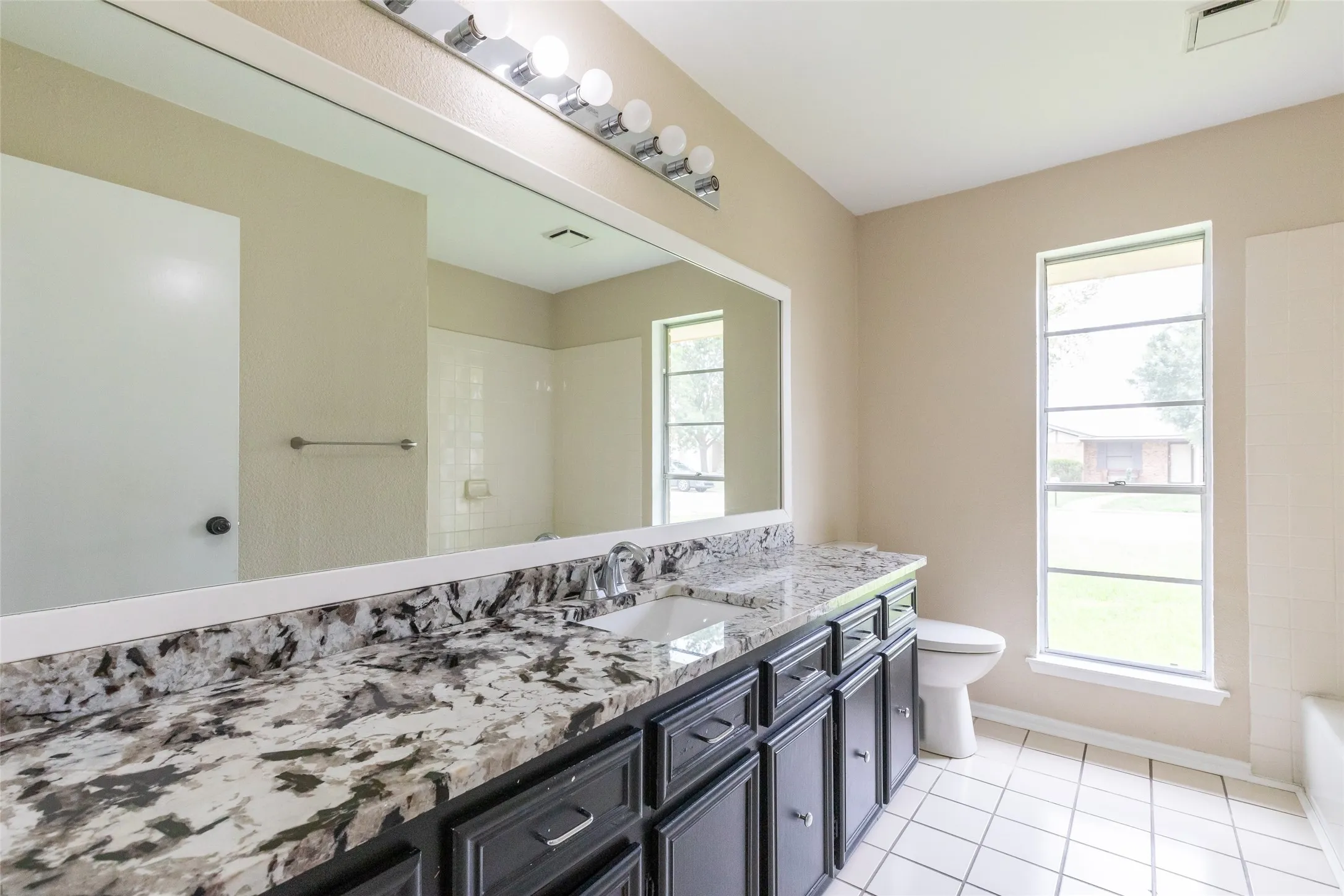 Bathroom vanity featuring a speckled countertop, integrated sink, and dark wood-finish cabinetry