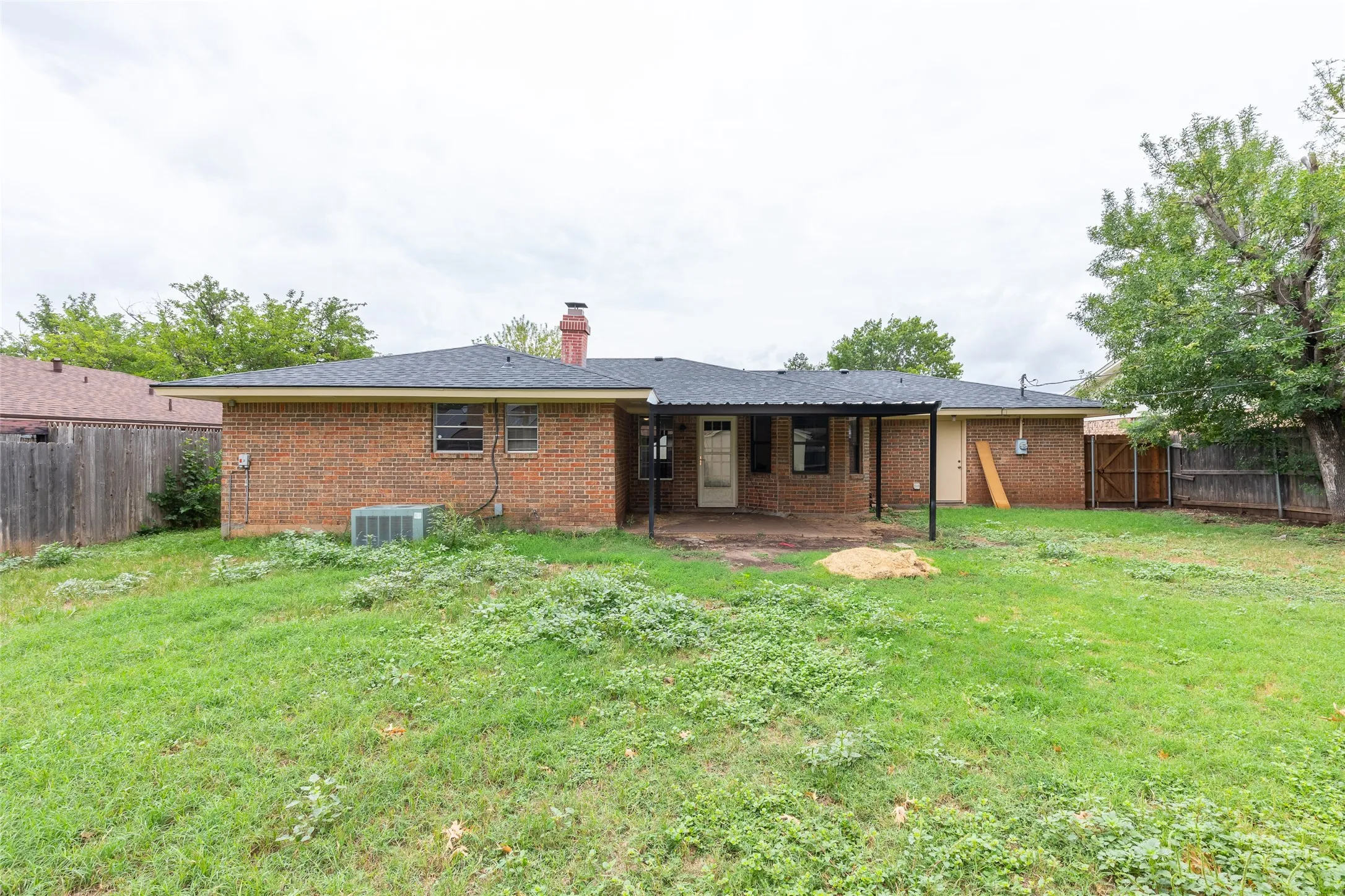 Expansive backyard featuring a brick exterior and a covered patio area