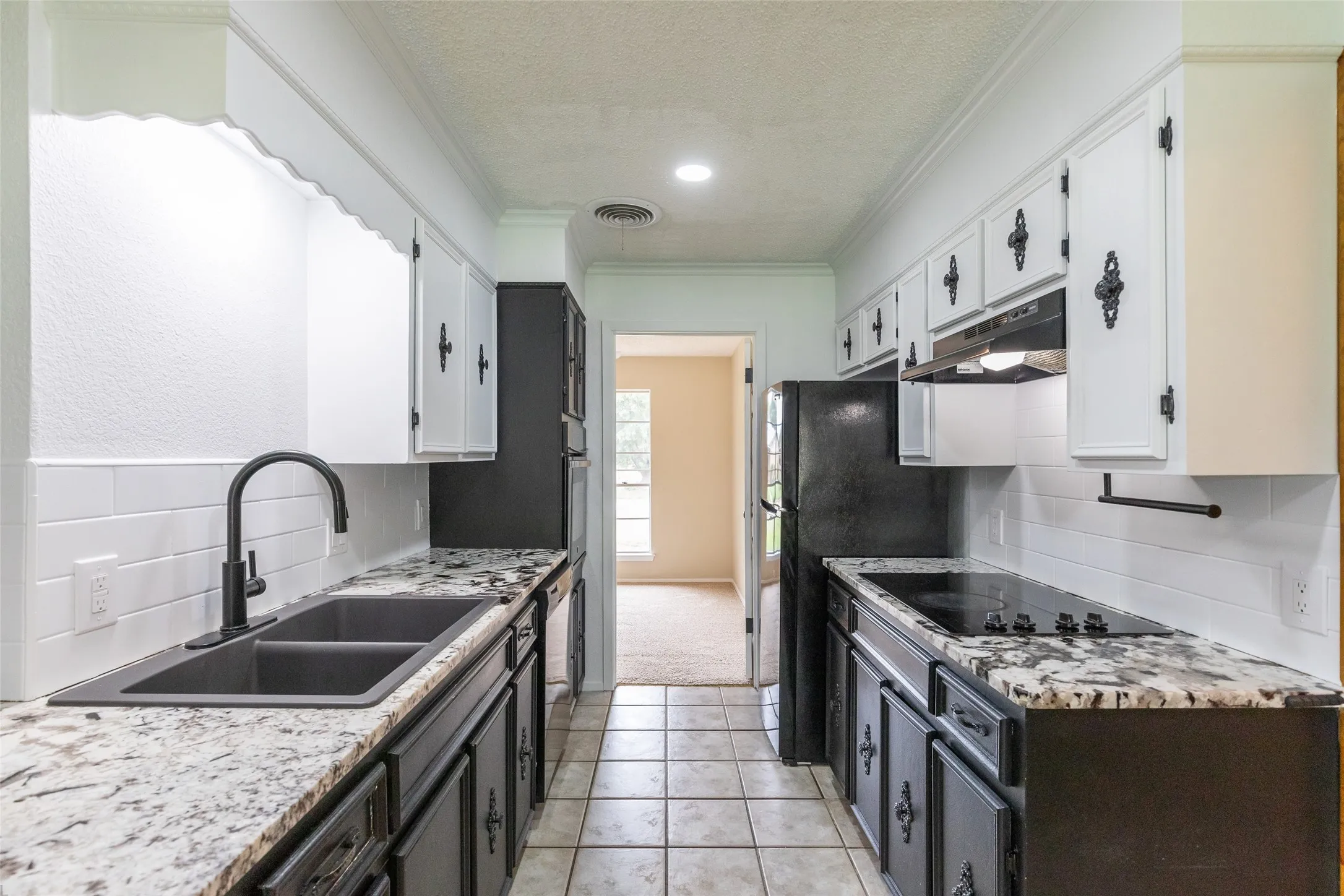 Galley kitchen featuring white upper cabinetry, dark lower cabinetry, and light-toned countertops